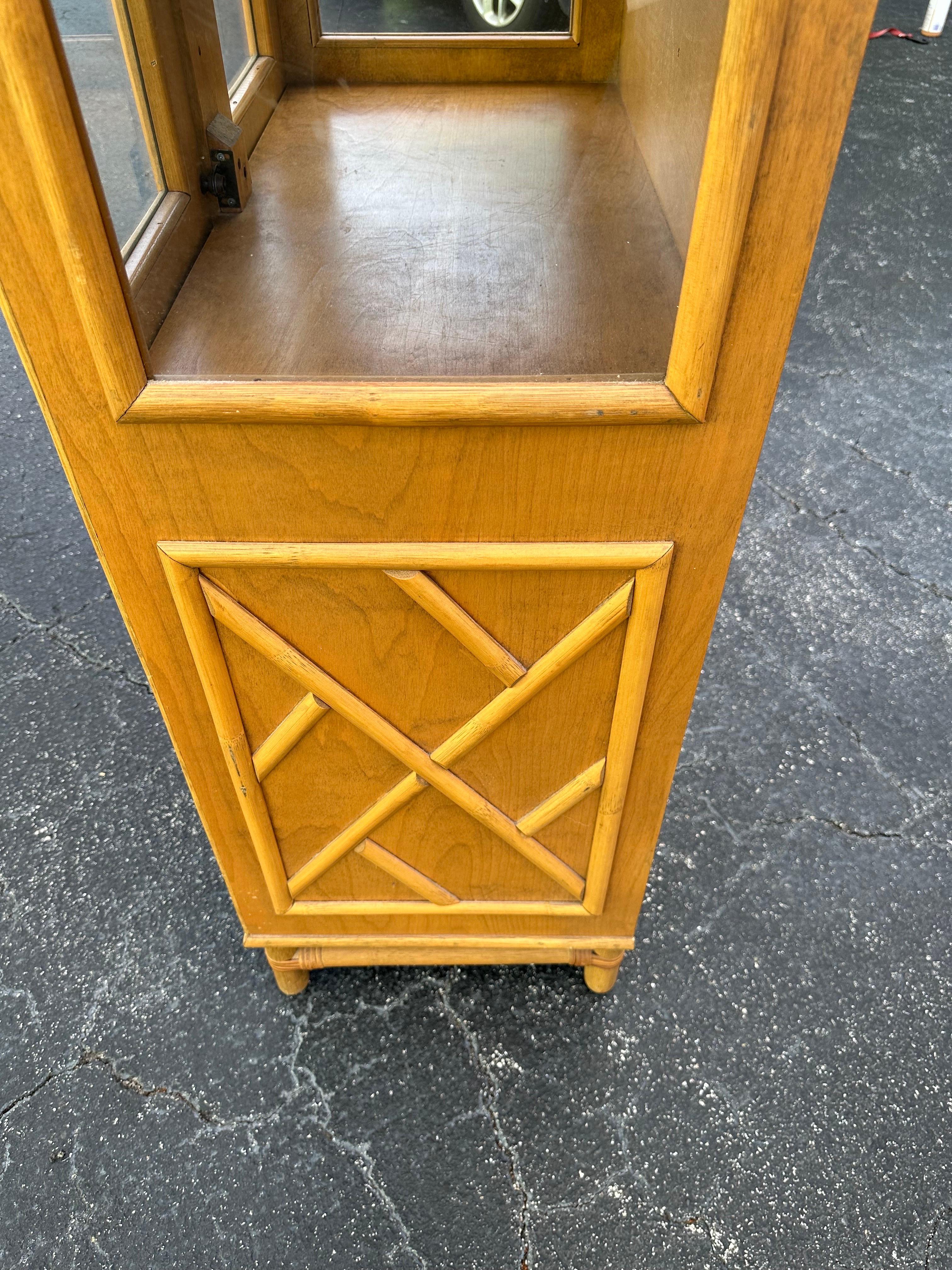 This vintage china cabinet is a unique addition to any home decor. The bamboo rattan fretwork design gives it a coastal Palm Beach boho Regency tiki vibe that is sure to catch the eye of anyone who sees it.  Includes a light to light up the glass