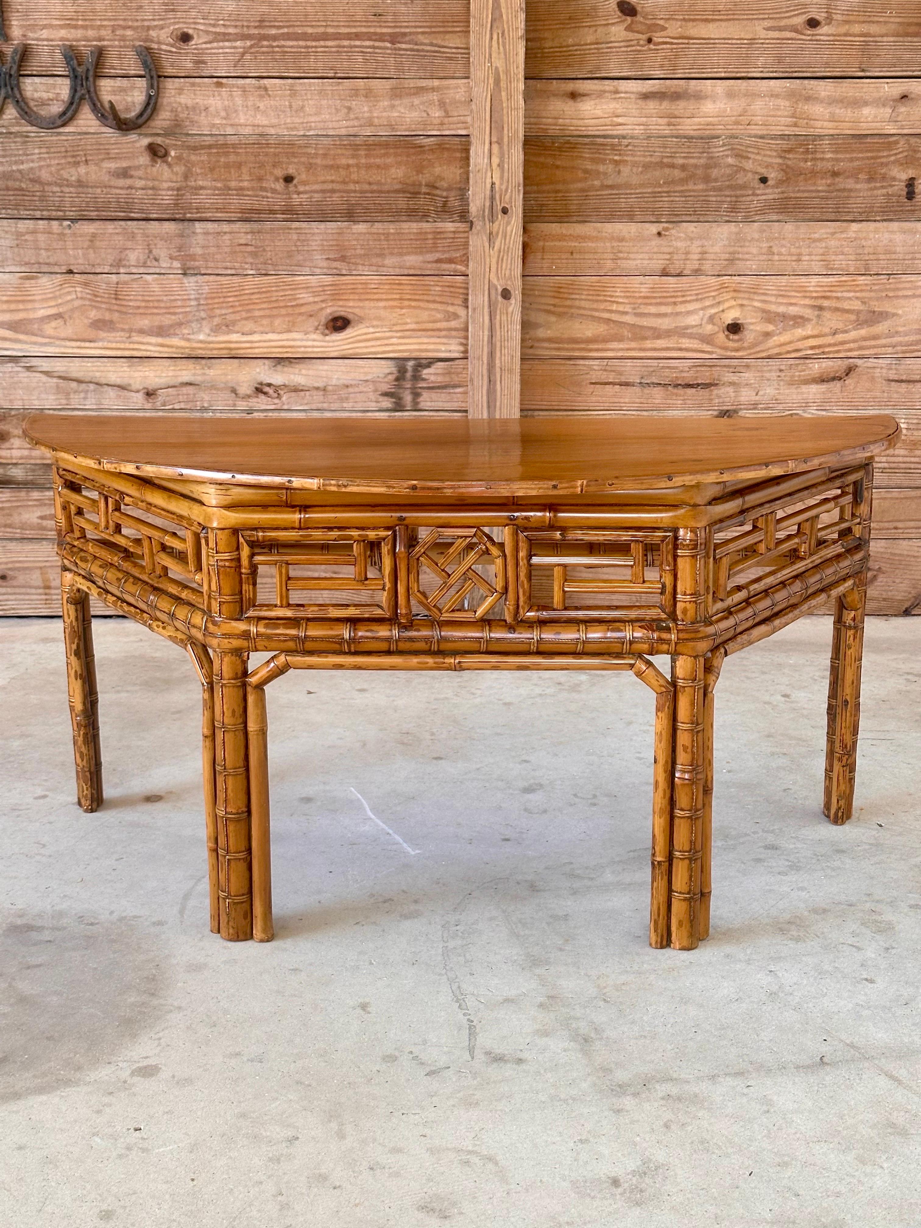 Introduce an element of refined elegance to your space with this Vintage Bamboo Chinese style demi-lune low profile center table.
The table features a distinctive open fretwork design, soft wood top, showcasing intricate craftsmanship inspired by