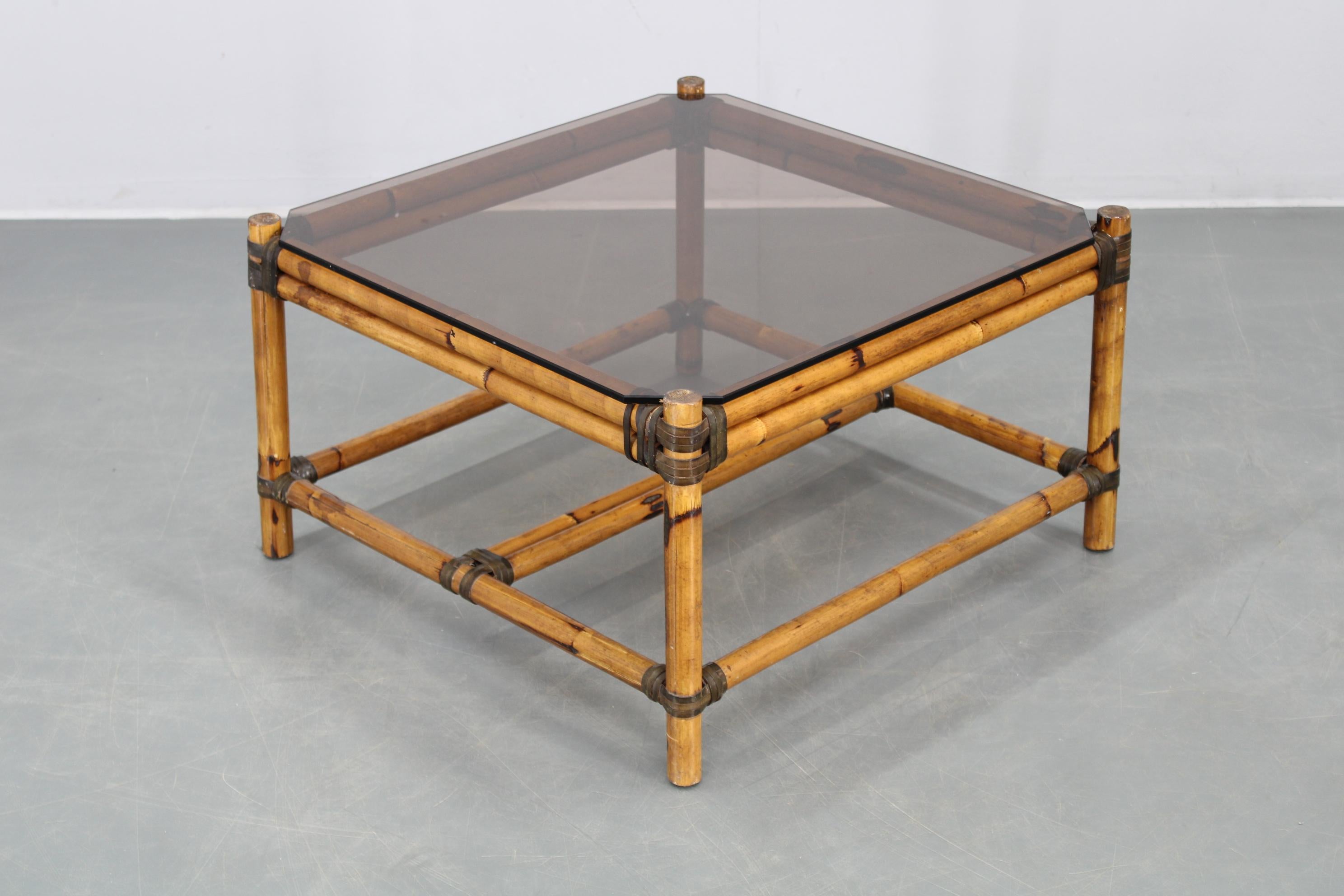 Charming square coffee table featuring a bamboo frame and smoked glass top, perfect for mid-century or bohemian interiors. Sturdy and stable, this piece blends natural warmth with retro appeal. 
Dimensions: Height 36 cm (14.17 in), Width 59 cm