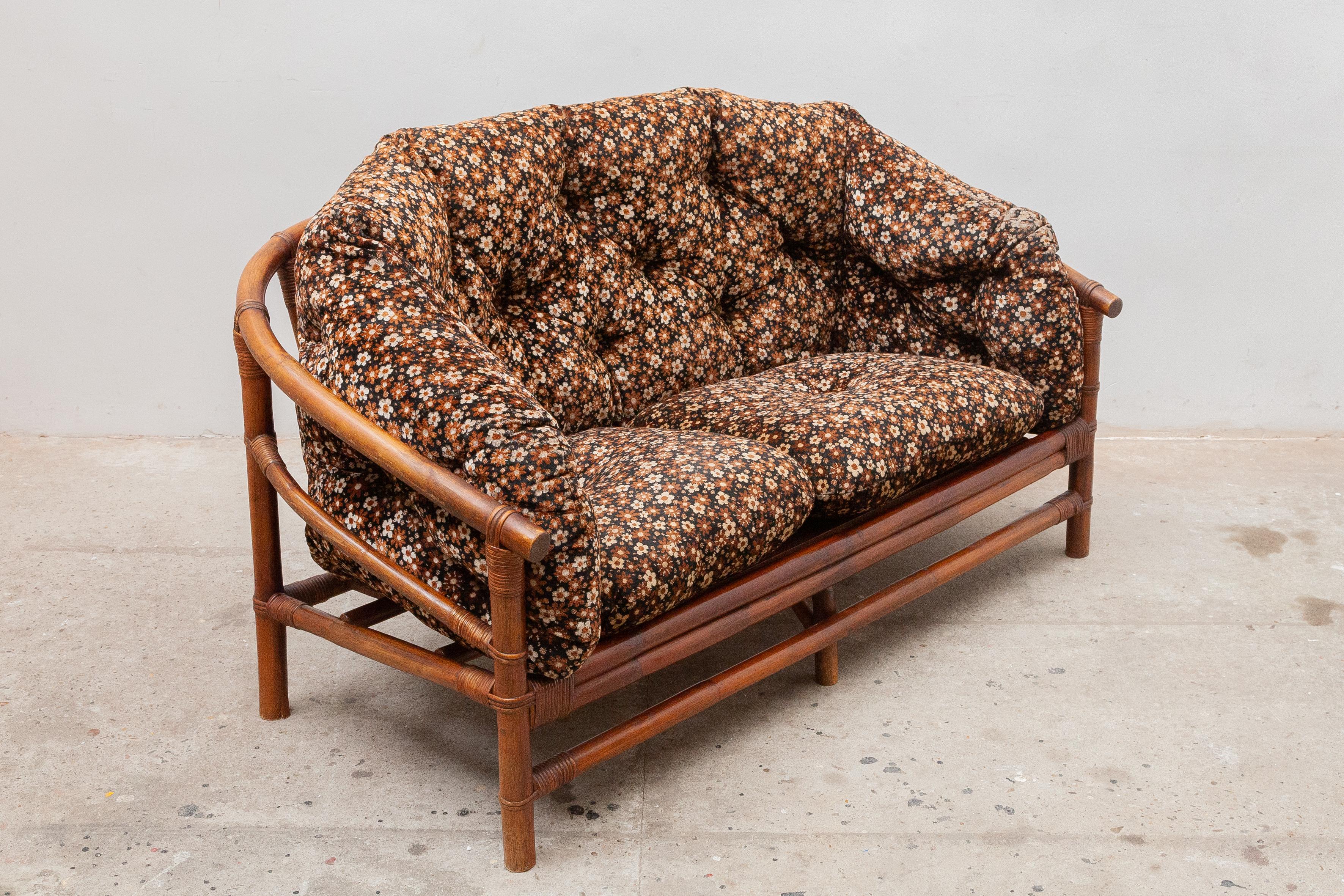 A beautiful original love sofa for your porch with an absolute sixties atmosphere. The furniture is handcrafted from darkened thick bamboo and teak seats draped with one-piece thick cushions in corduroy upholstery with a cute typical sixties floral