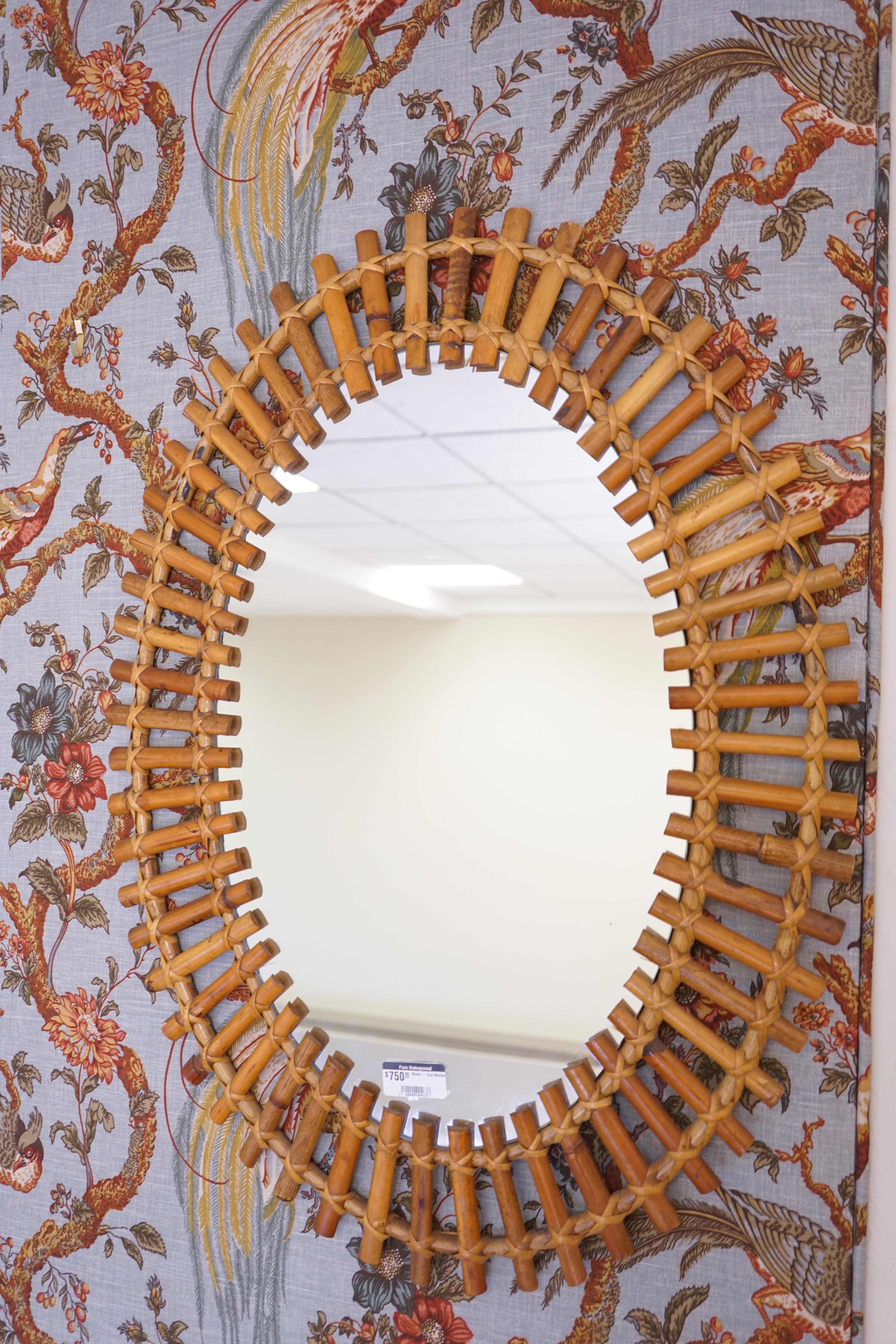Vintage oval mirror framed by bamboo.