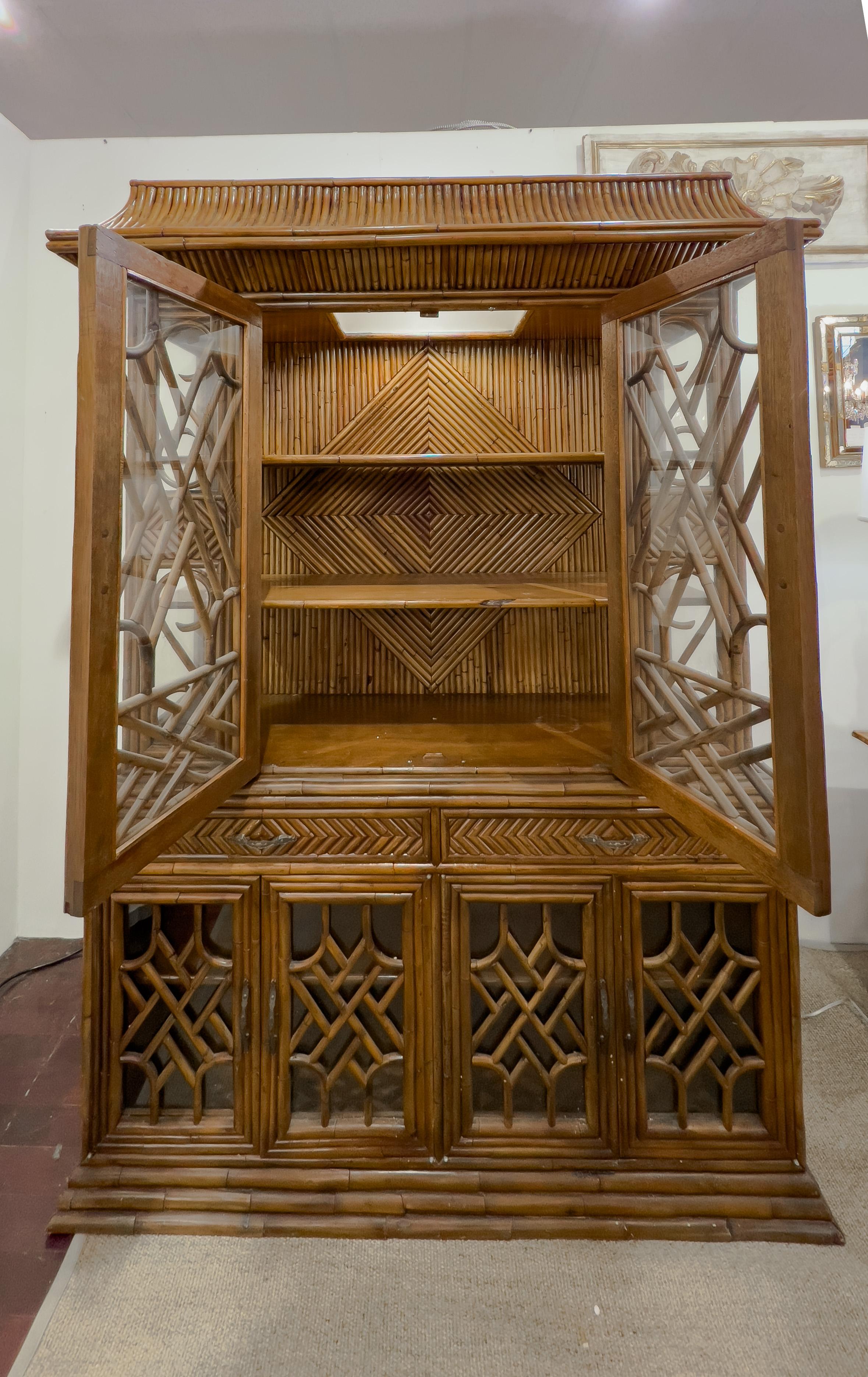 Vintage bamboo pagoda shape cabinet in two pieces with 2 interior shelves on the the top and 1 on the bottom. This piece also has 2 glazed doors on the top, 4 on the bottom and 2 drawers in the middle. The top also has glass on the sides.  

This