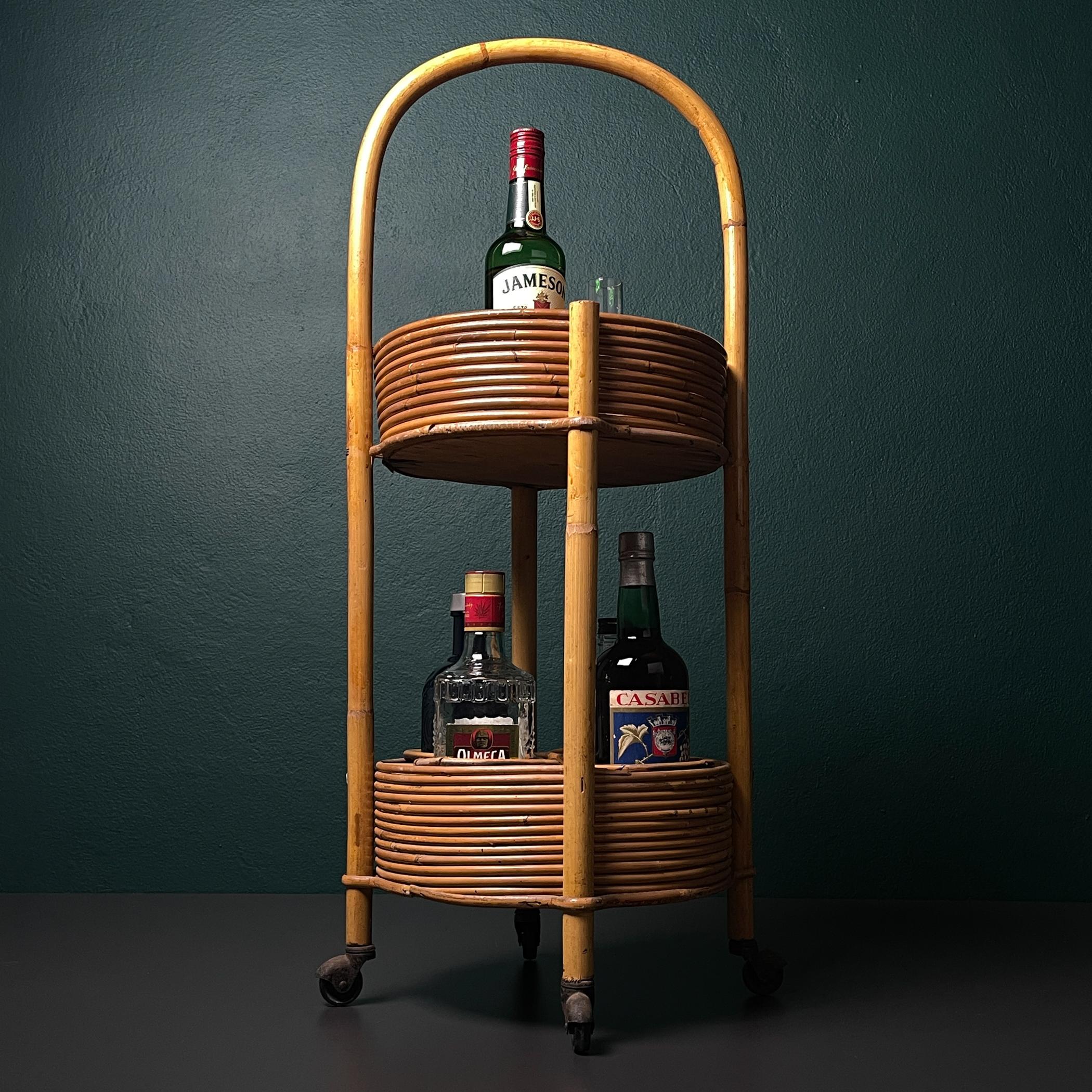 Amazing rattan and bamboo bar cart made in Italy in the 1960s.
The bottom level is designed for storing bottles, while the top one has a useful handle for moving the trolley.

The vintage trolley is in good vintage condition.

Dimensions:
Width: 35