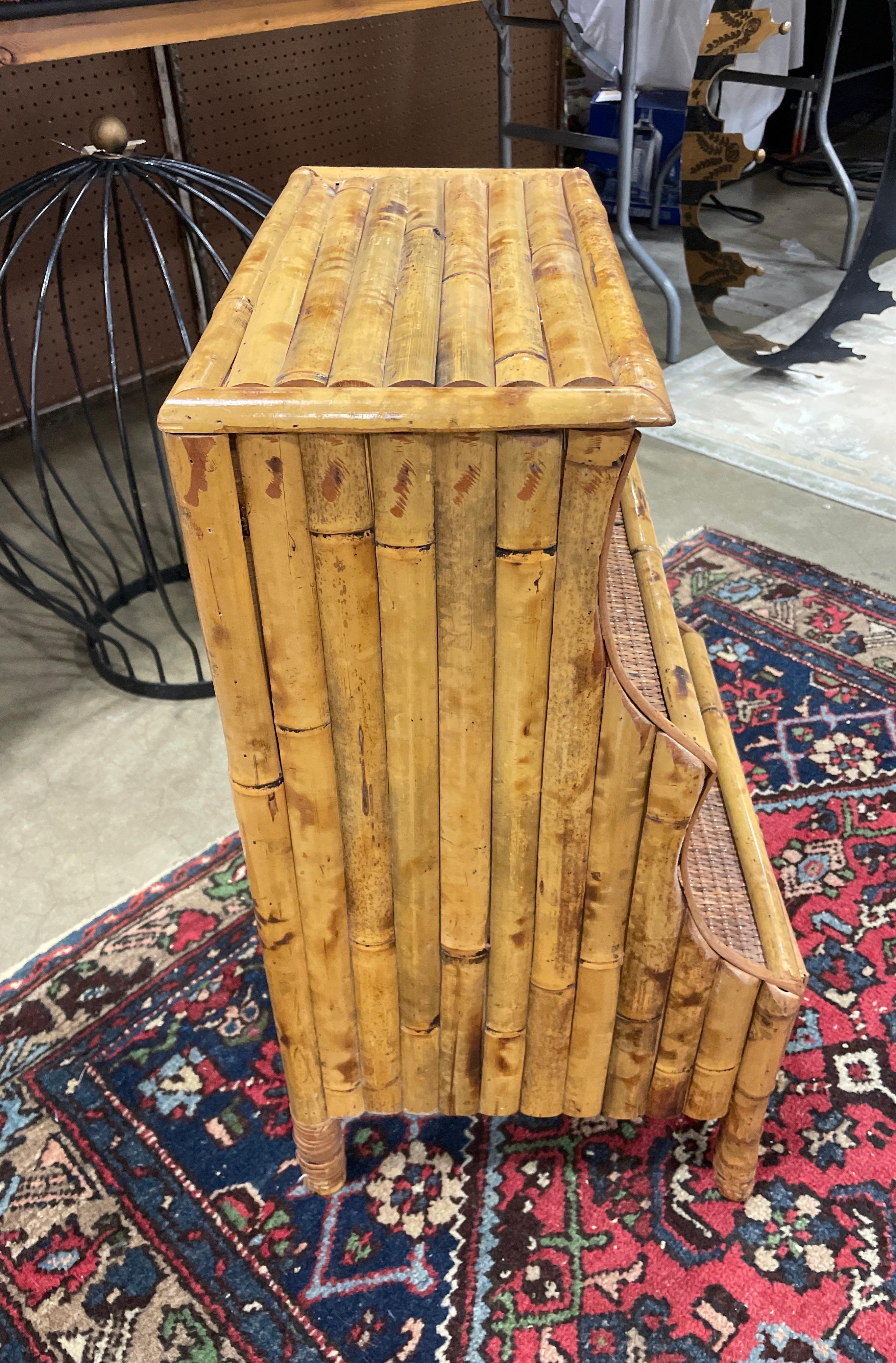 Table d'appoint vintage en bambou avec un tiroir. Cette belle pièce possède deux étagères en plus du plateau et les pieds avant sont munis de pieds racines.