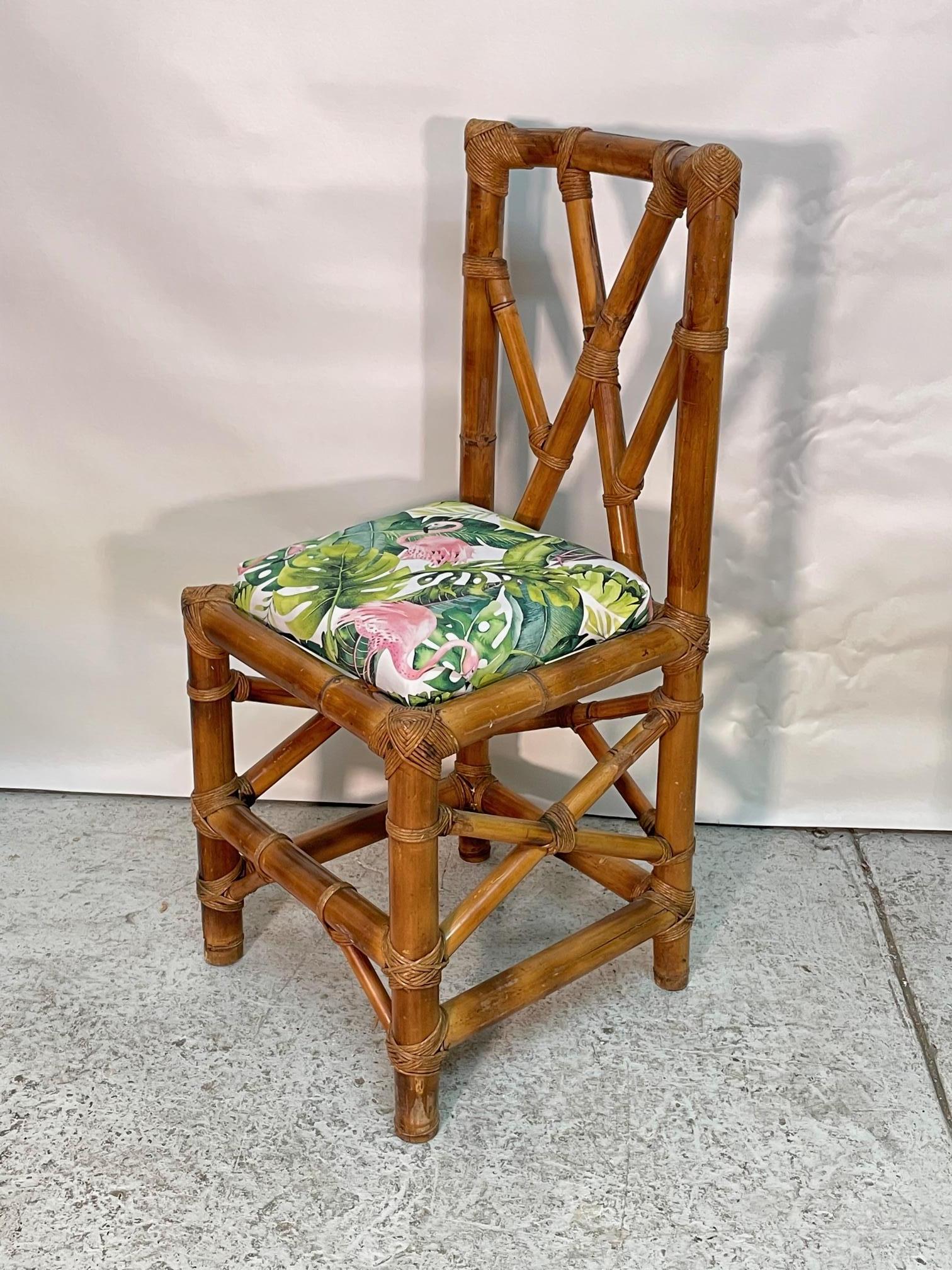 Vintage bamboo game table set features an octagon shaped table with smoke glass top and six dining chairs. Could also be a breakfast dining set. Chairs are upholstered in new fabric, a fun, tropical print with pink flamingos. Intricate fretwork in a