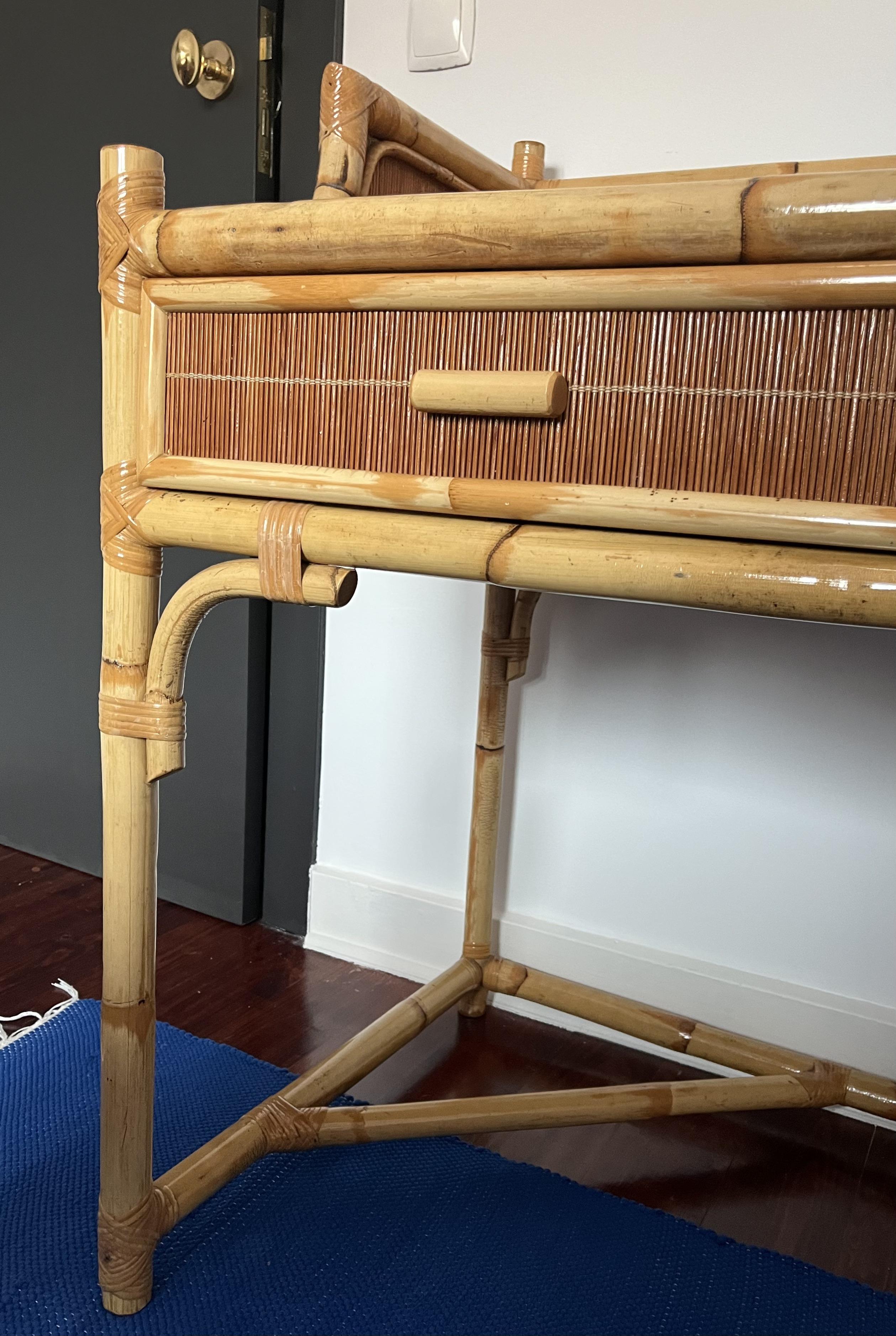This vintage bamboo writing desk blends natural elegance with functional design. Featuring a solid bamboo frame and a woven rattan paneling, it showcases expert craftsmanship with beautifully curved details along the top edges. The desk is equipped