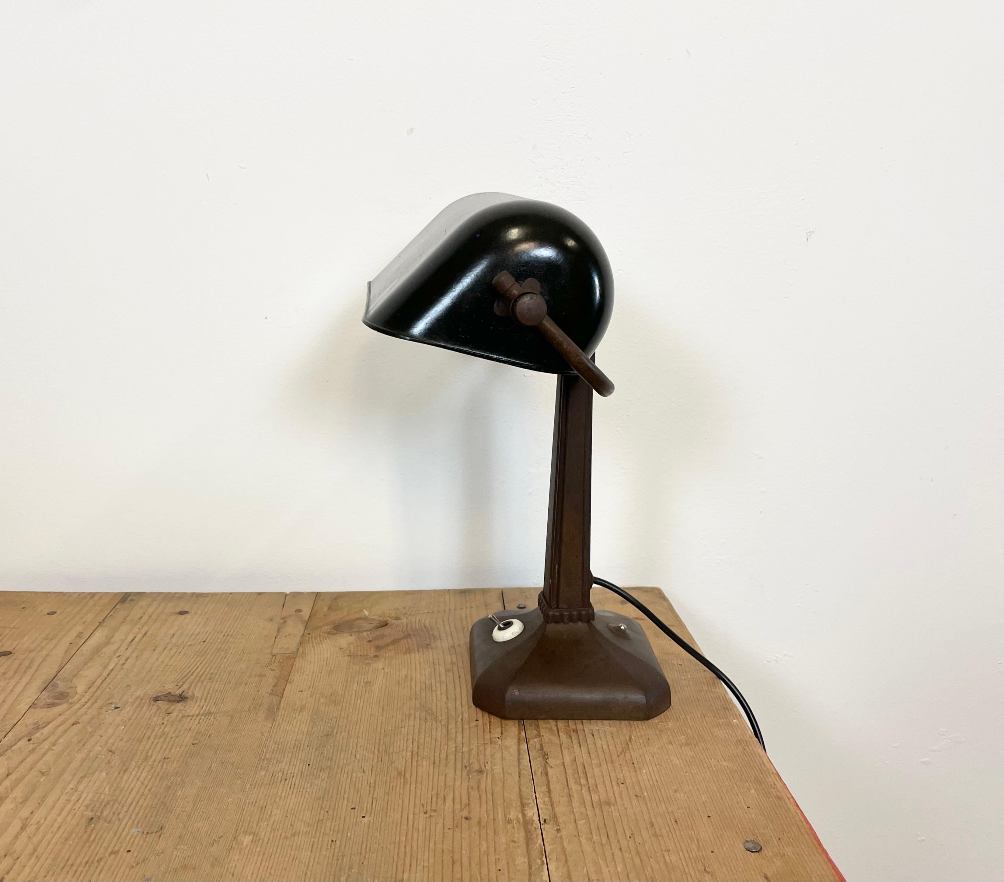 This vintage table lamp was made in former Czechoslovakia during the 1950s. It features a black bakelite adjustable shade  and a brass base with switch. The porcelain socket requires standard  E 27/ E 26 ligh bulbs. New wire. Fully