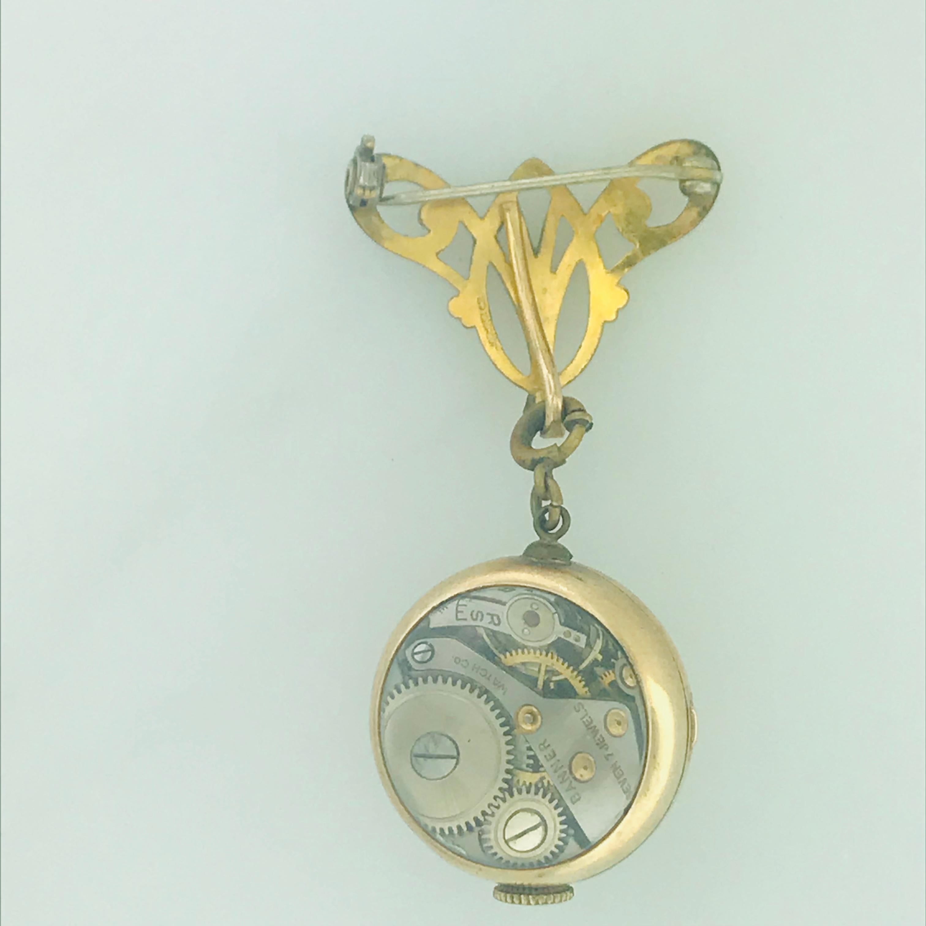 Eine alte Anstecknadel und Uhr, die abnehmbar und anbringbar ist. Dieses Stück ist Vintage und in sehr gutem Zustand. Die Uhr ist eine Schweizer Banner-Uhr mit skelettiertem Boden und 7-steinigem Antrieb. An der Uhr befindet sich ein einfach zu