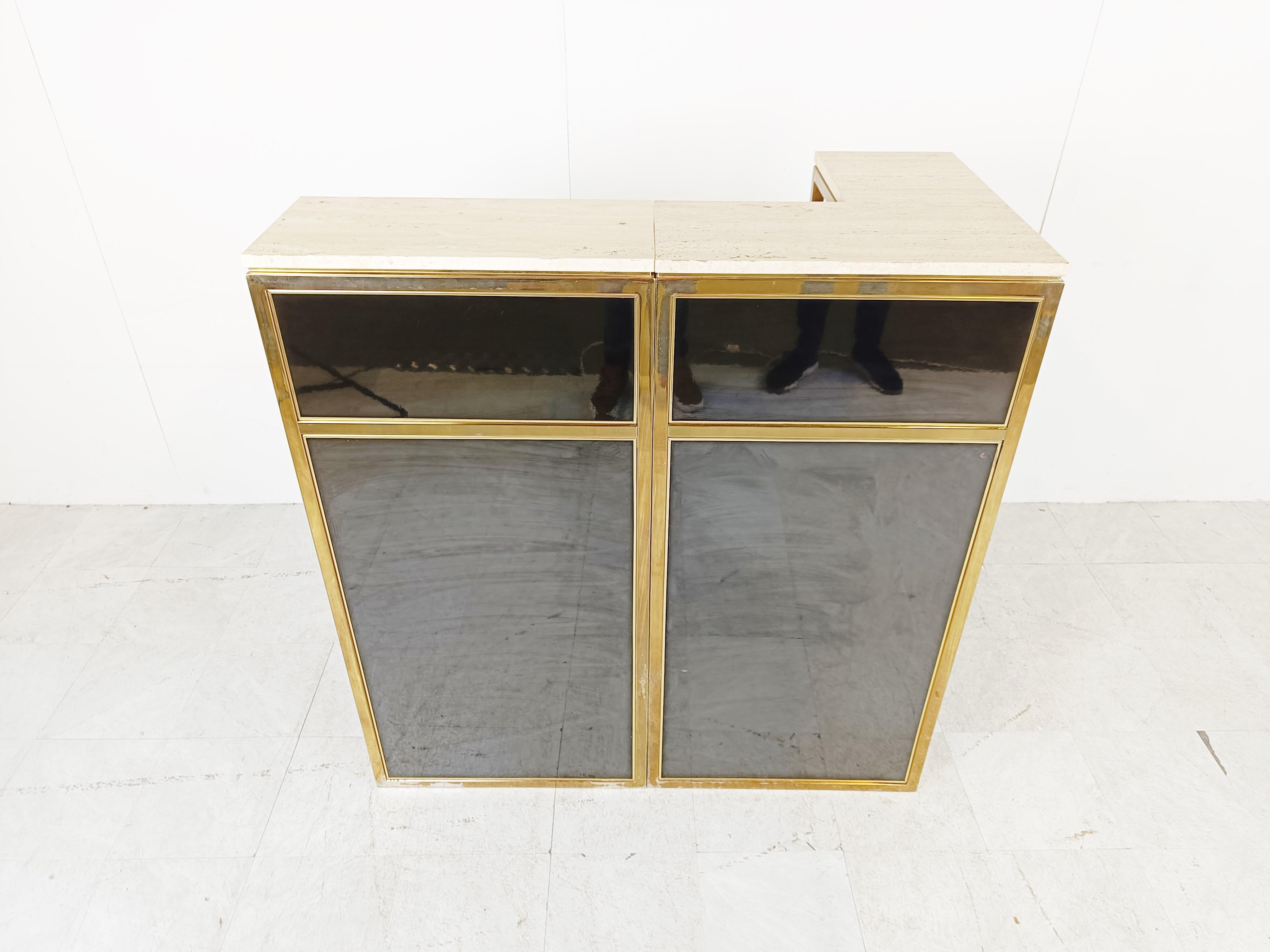 Hollywood regency 2-module bar counter made brass, black lacquer and a travertine top.

This high quality bar is a real eye catcher and has a very luxurious appeal.

Its a nice and small bar counter with a corner, ideal for an appartment or
