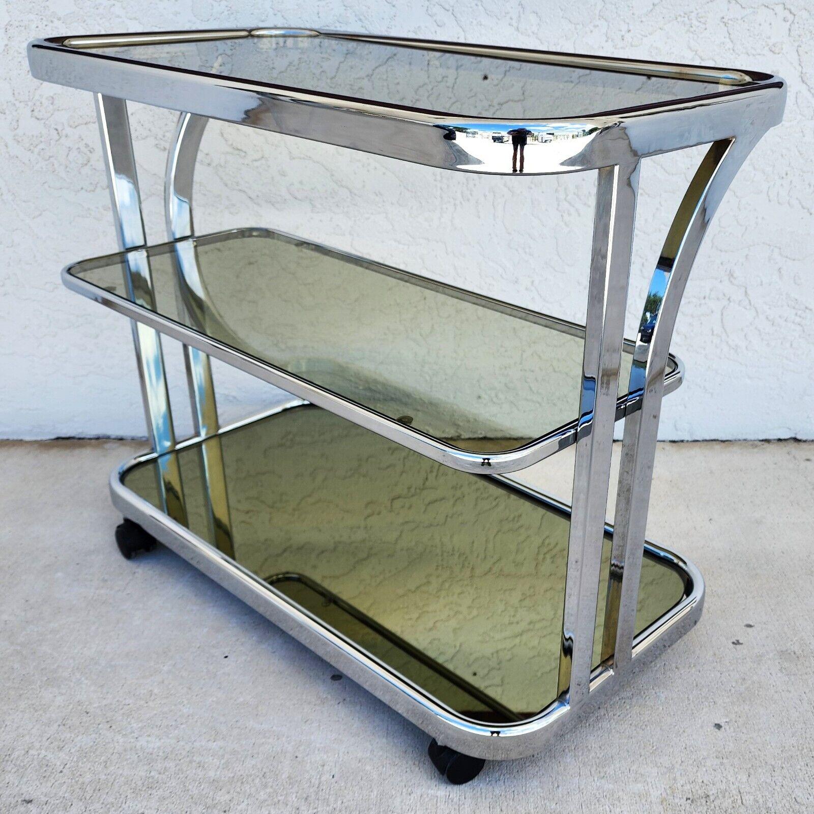 Vintage Rolling 1970s Chrome Bar Cart with Smoked Glass on Top 2 Shelves and Smoked Mirror on Bottom
The second shelf is inset so there is room for taller bottles there. Chrome is high-quality and is not plated.

Approximate Measurements in