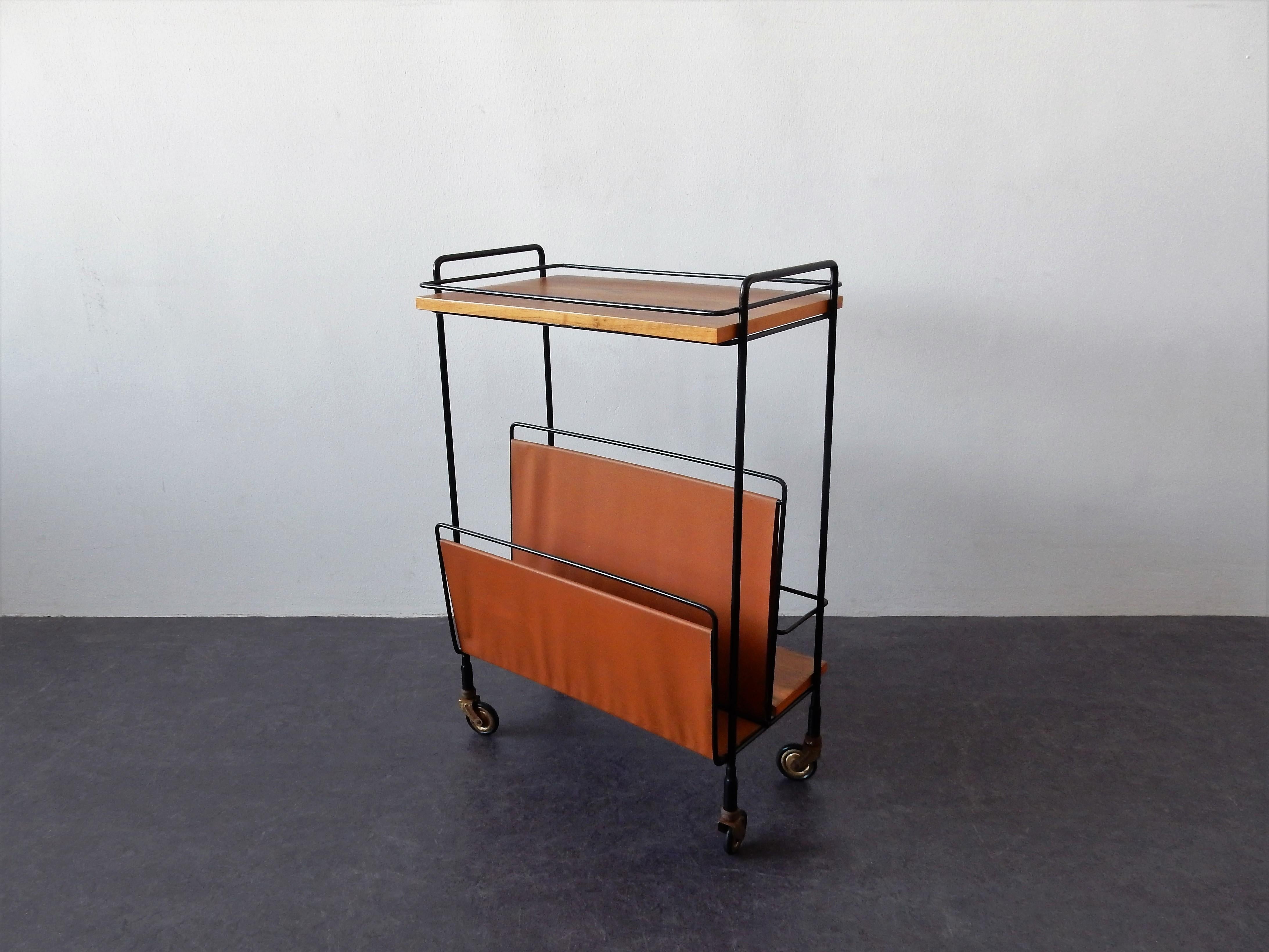 This is an excellent and stylish vintage trolley made in the 1960s. It has 2 wooden shelves, a metal frame with a compartment for bottles and a magazine rack in leather-look. The trolley stands on 4 small wheels. This trolley has been superficially