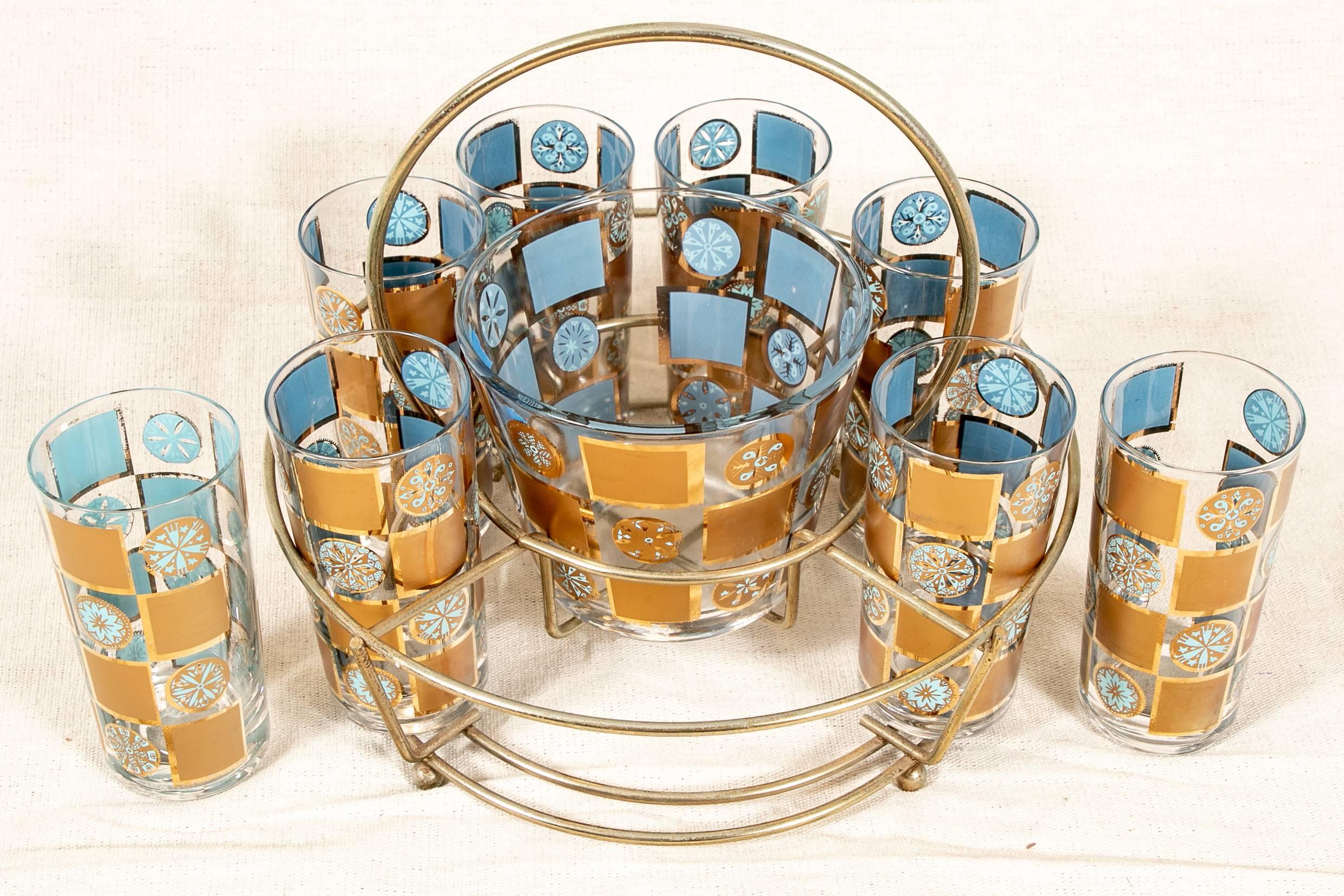 Vintage bar cart with match glassware, two-tiered circular chrome cart with blue and gilt decorated glass tiers with rosettes and squares, along with matching tall glasses with a glass bowl in the center displayed in a removable chrome stand with a