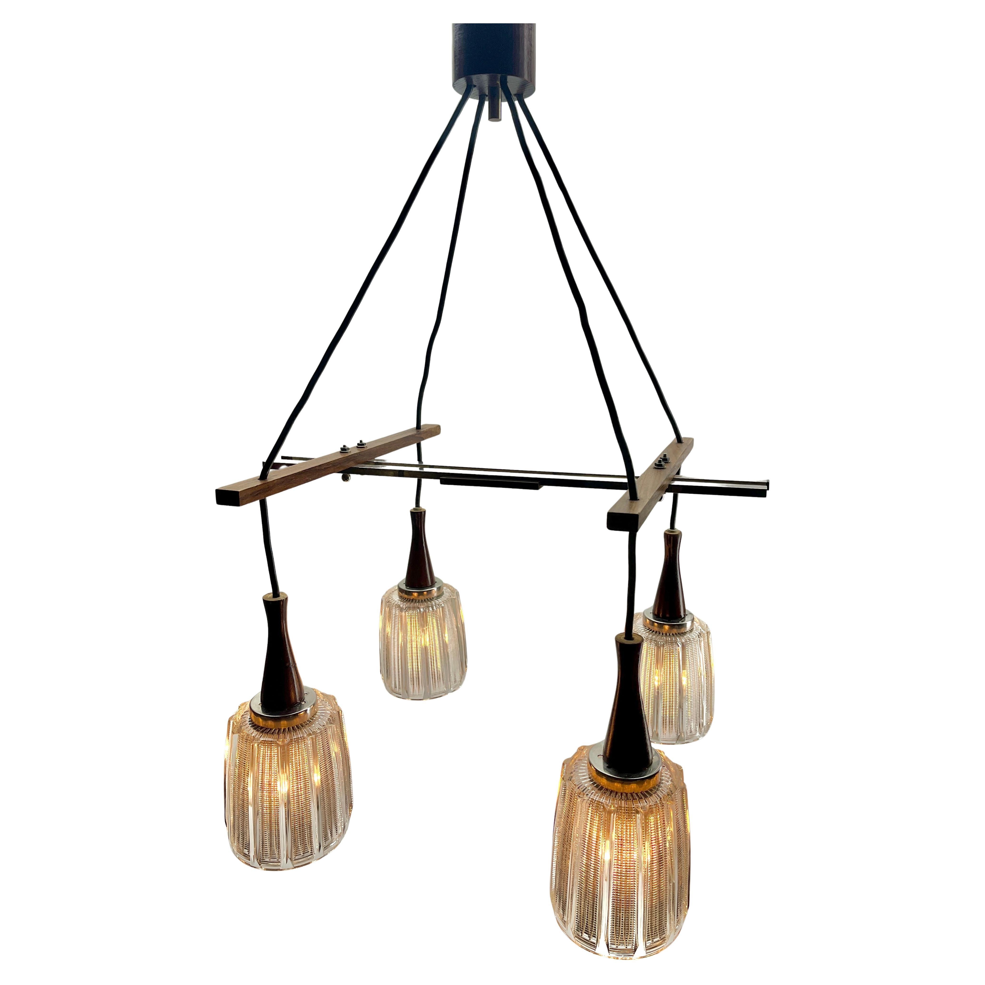 Lustre bar vintage, 4 abat-jours en verre avec des raccords chromés, avec une structure en teck dans le style de Kalmar.
En bon état et en parfait état de fonctionnement. Raccord E27.
La puissance des ampoules peut varier de 25 à 60 watts. 
Equipé