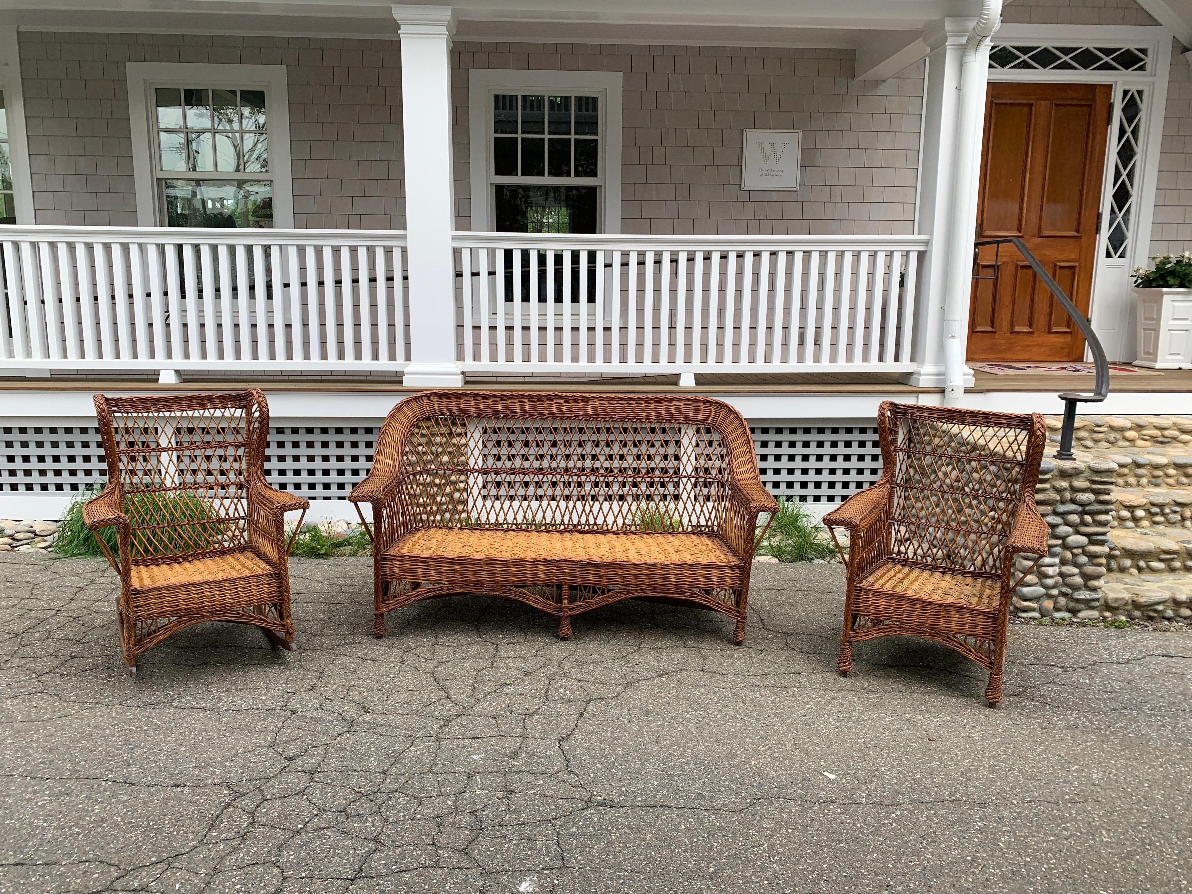 An antique wicker set woven of willow with a natural stained finish.  Set includes a three seat sofa and a wing back chair and rocker. These pieces will do well outside under cover. They are sturdy and have been cleaned and resealed.  We can arrange