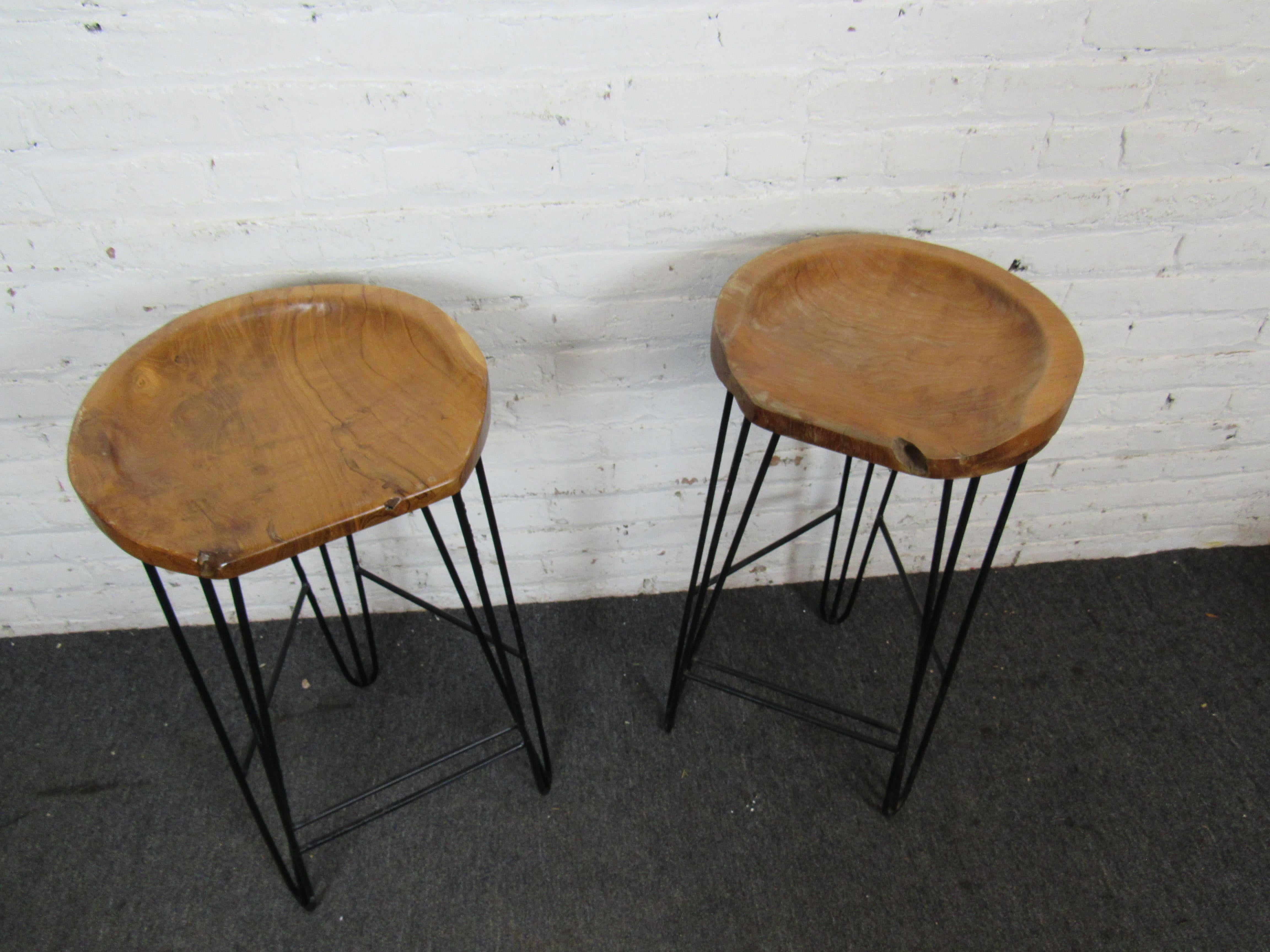This pair of unique vintage bar stools combines sculpted wooden seats with iron bases. Please confirm item location with seller (NY/NJ).