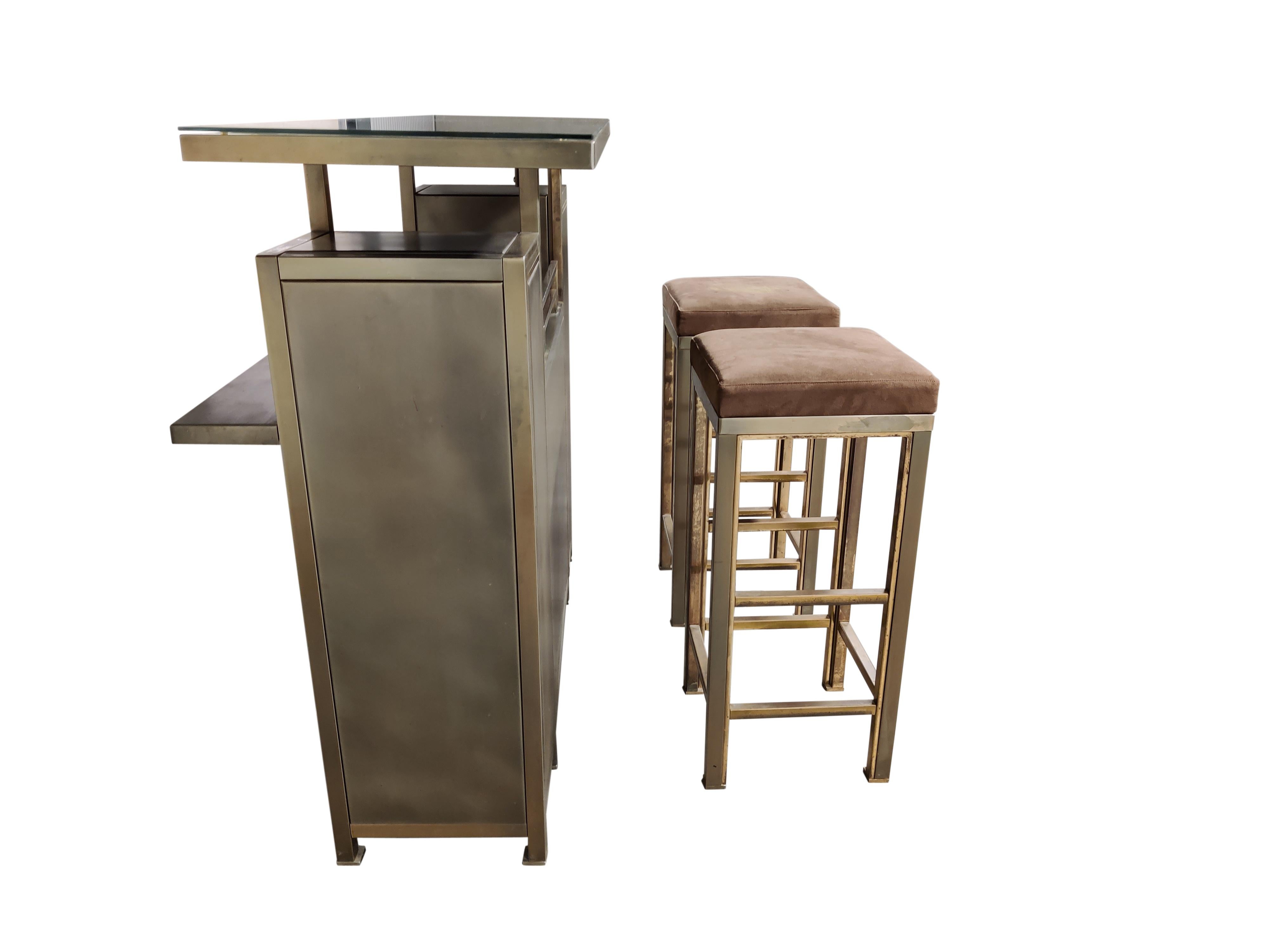 Luxury bar counter with two bar stools in brass and brushed steel.

The stools have their original velvet upholstery with some discoulouration, we can have them reupholstered if requested. But they are usable as they are.

The pieces has the