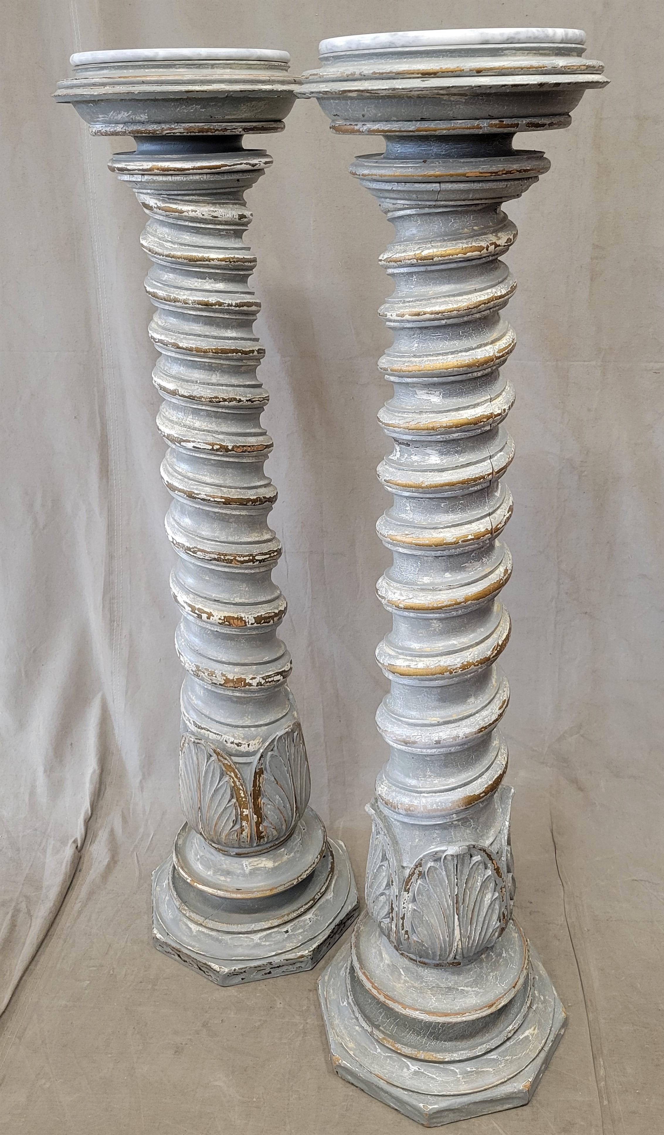 A stunning pair of vintage barley twist pillar plant or sculpture stands with distressed French gray paint with gold and white accents. Carrera marble tops add a classic touch and a flat surface for plants or sculptures. Note the carved palm motif