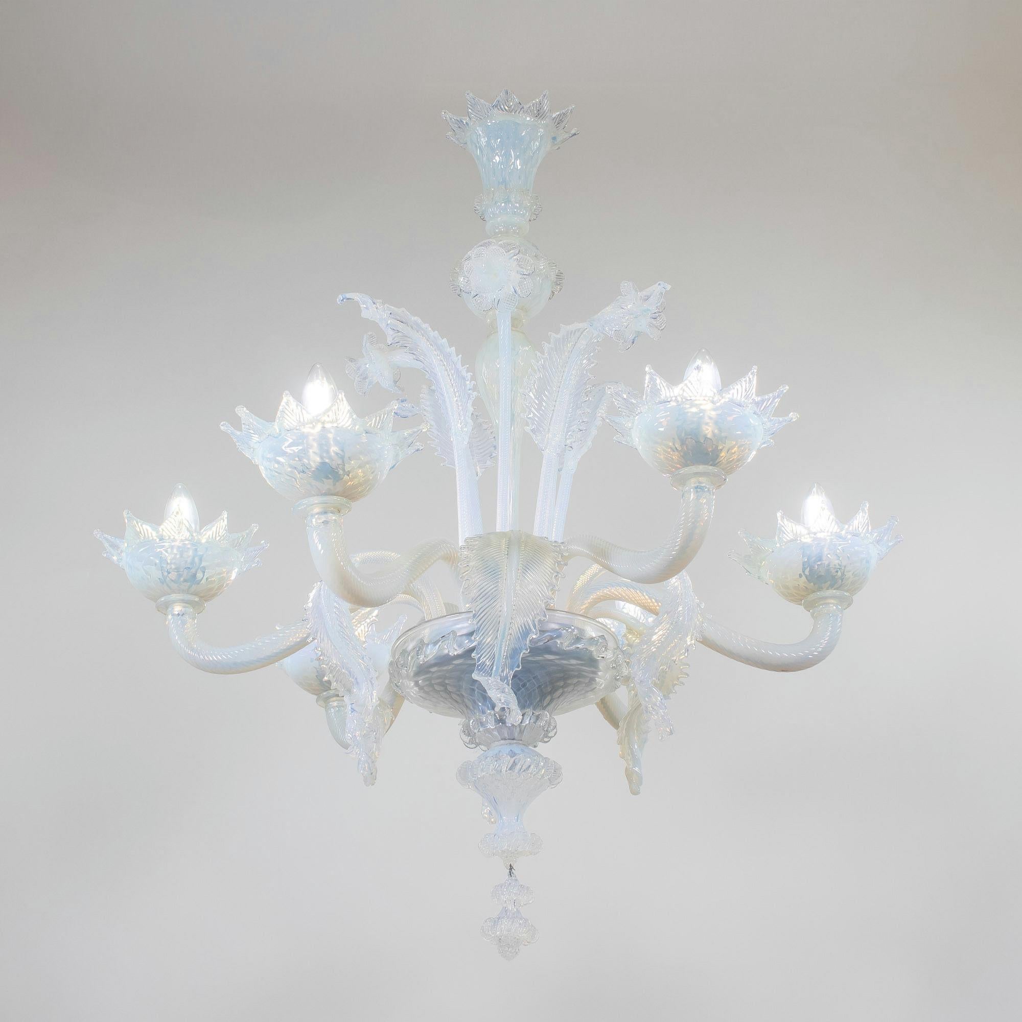 Esta araña de Murano opalina de estilo barroco vintage, hecha a mano, tiene seis brazos articulados con copas adornadas con hojas. El cristal opalino lechoso vira hacia un color azul claro con sutiles cambios de luz. Flores y hojas embellecen esta