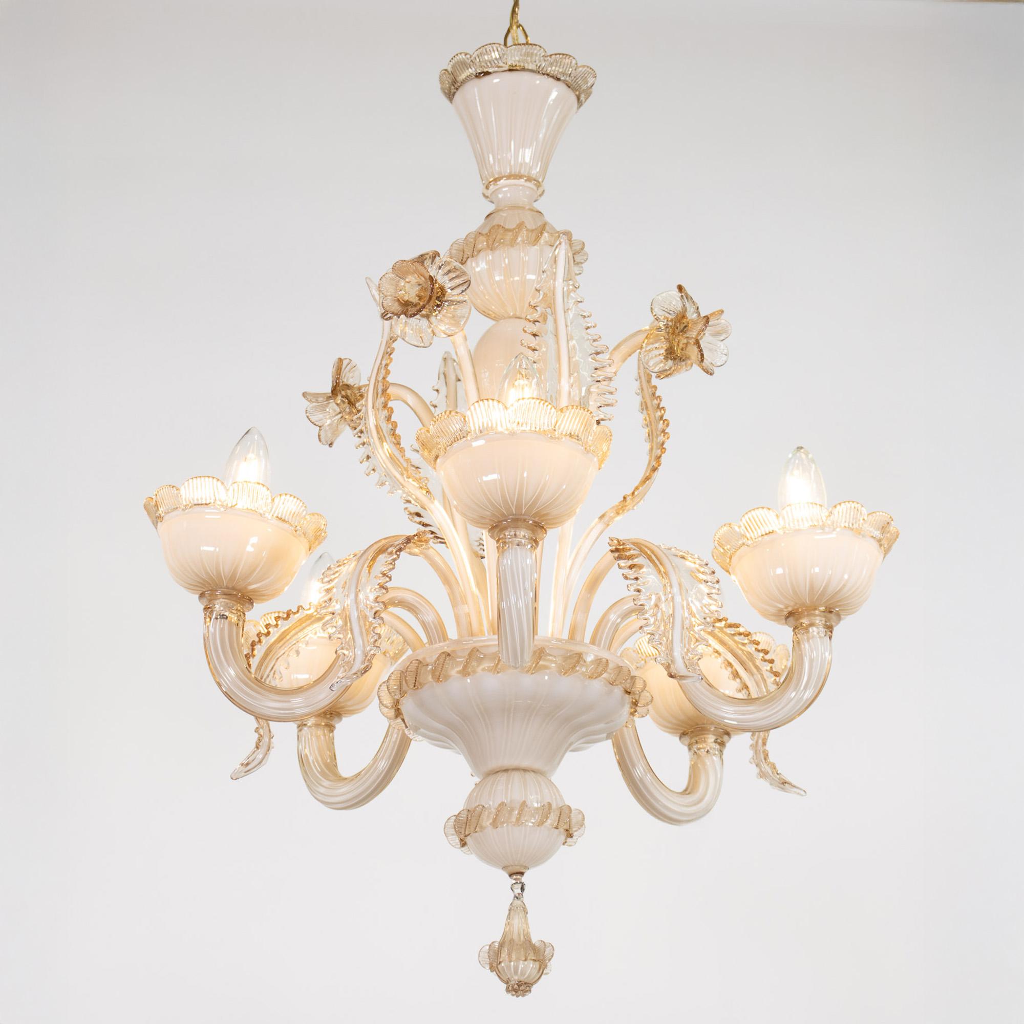 Questo squisito lampadario in vetro di Murano color latte e miele mette in mostra la maestria dell'artigianato del vetro veneziano. Presenta una colonna centrale a bulbo con dettagli di germogli, qui stilizzati con narcisi e foglie, e cinque bracci
