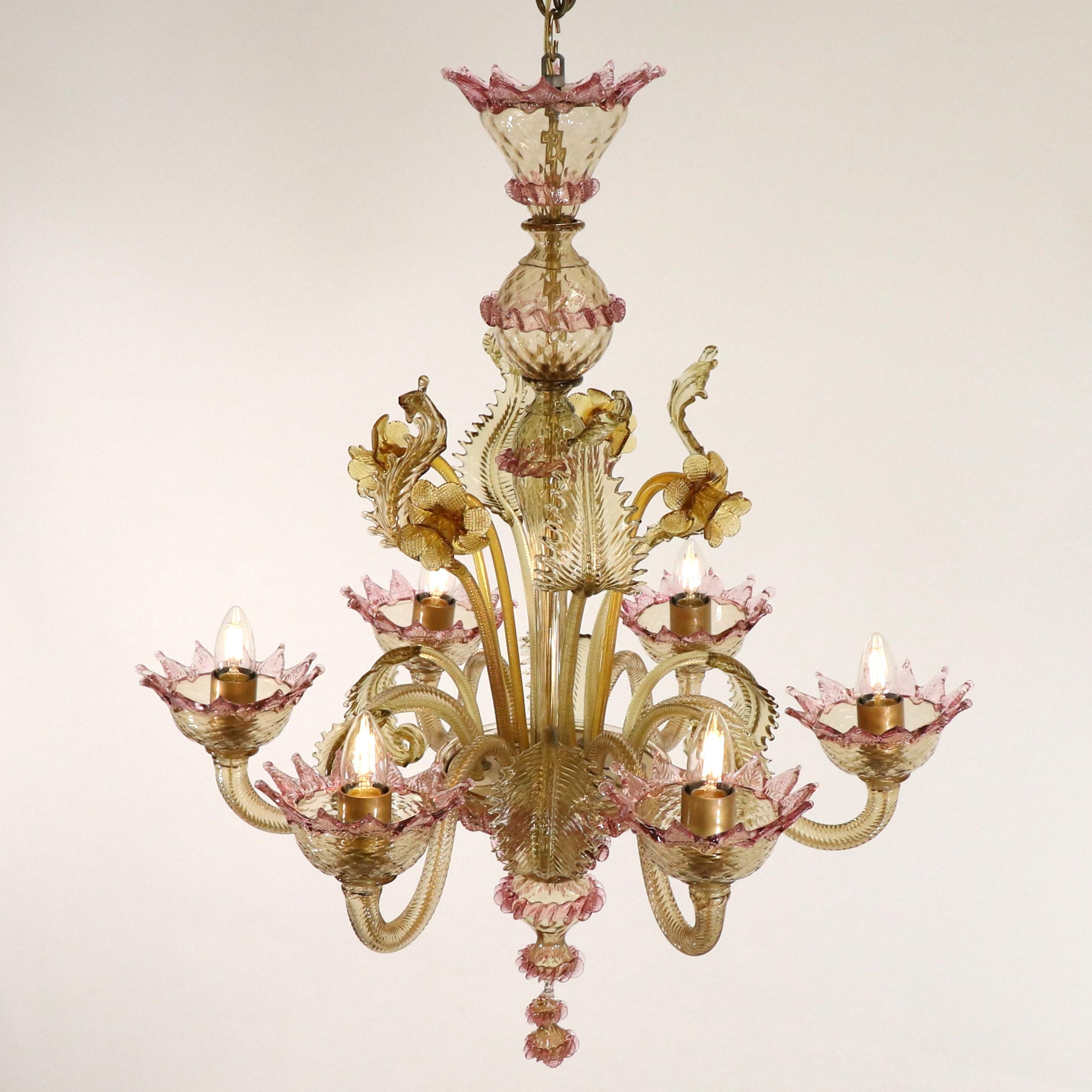 This exquisite two-toned Murano glass chandelier showcases a mastery of Venetian glass craftsmanship. Featuring a bulbous center column with sprouting details, stylized here with daffodils and leaves, and six scroll arms that hold bobeches with