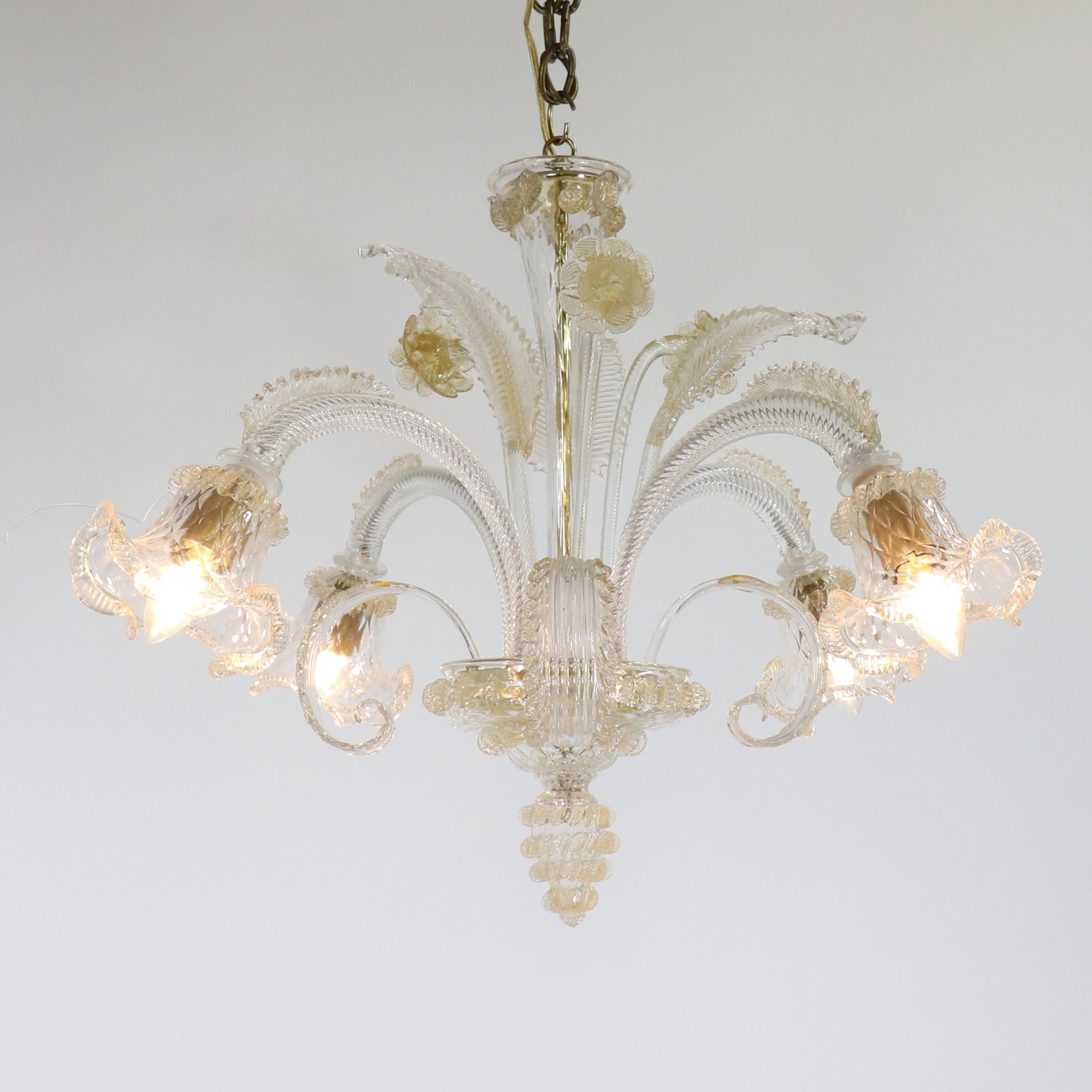 This spectacular gold-infused Cristallo Murano chandelier features four scroll arms with tri-lobed cups, elegantly styled with tiers of daffodils and leaves. The glasshouses on the island of Murano are renowned for their highly ornamented glass
