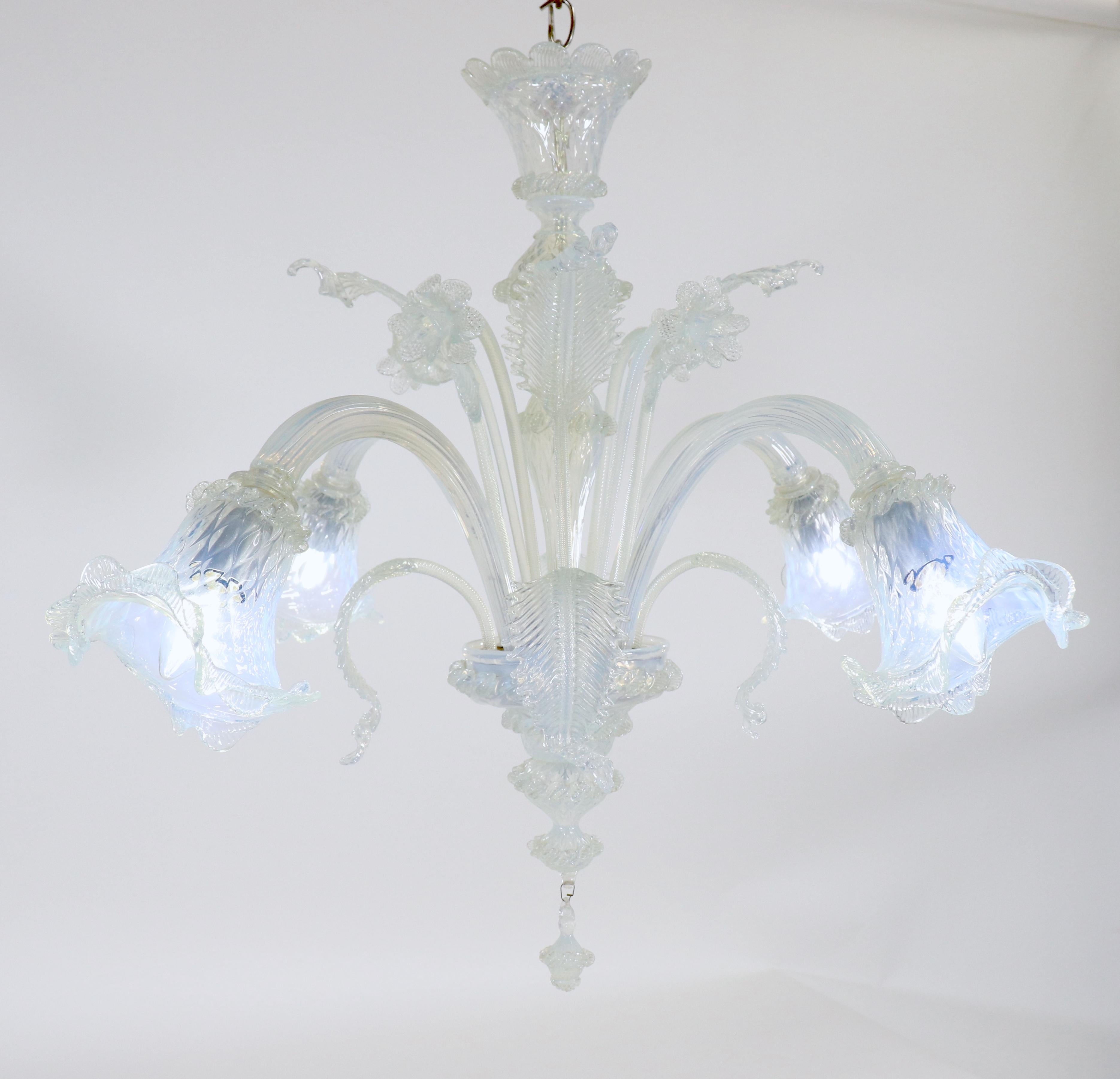 Questo piccolo e splendente lampadario opalino di Murano, realizzato a mano, ha quattro bracci flessuosi con coppe trilobate in evidenza. Il vetro opalino vira verso un colore azzurro con sottili variazioni di luce. Narcisi e foglie abbelliscono