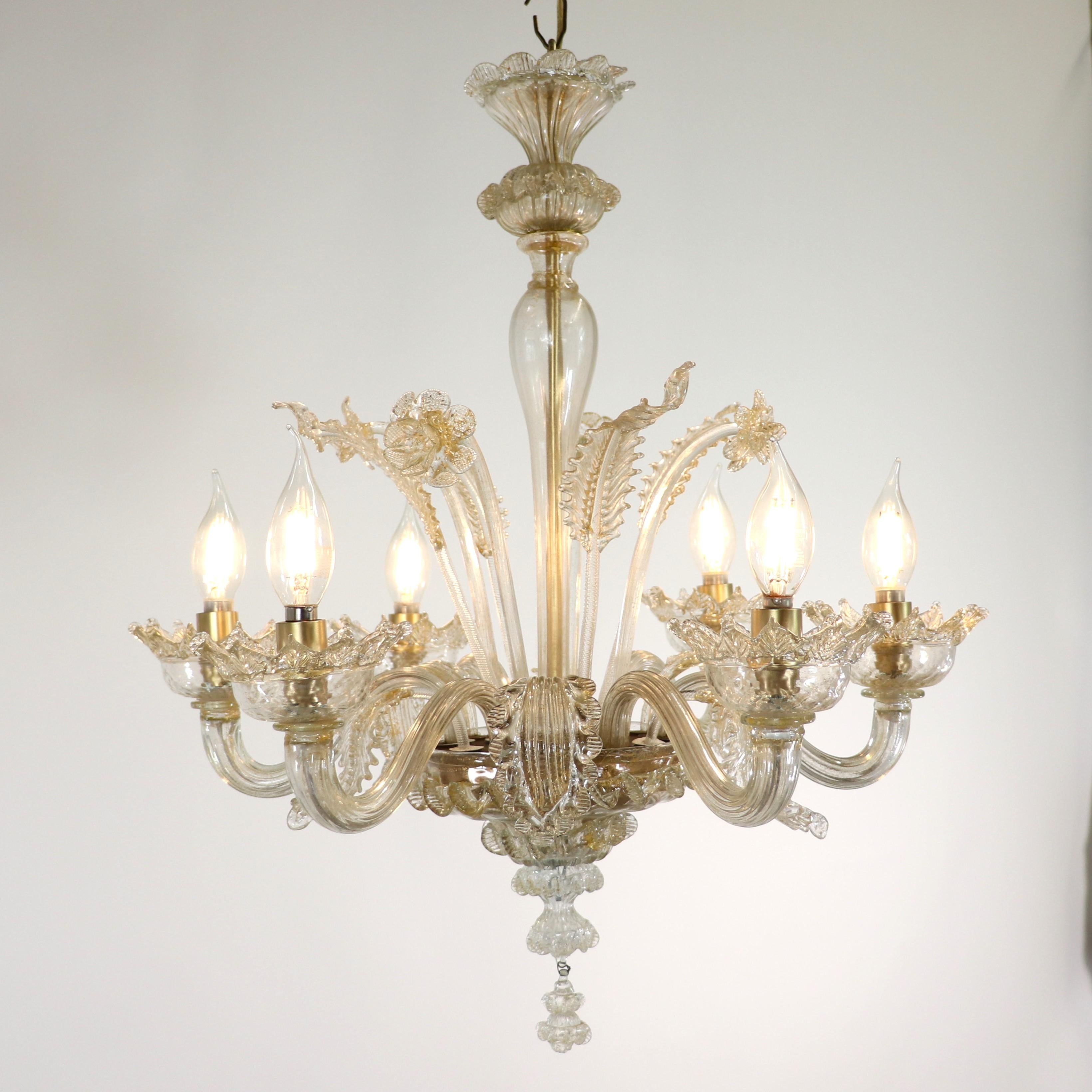 This handcrafted gold-infused cristallo Murano chandelier has six scroll arms holding bobeches with petal-shaped trim. Featuring a bulbous center column stylized here with daffodils and leaves. The glass houses on the island of Murano are famous for
