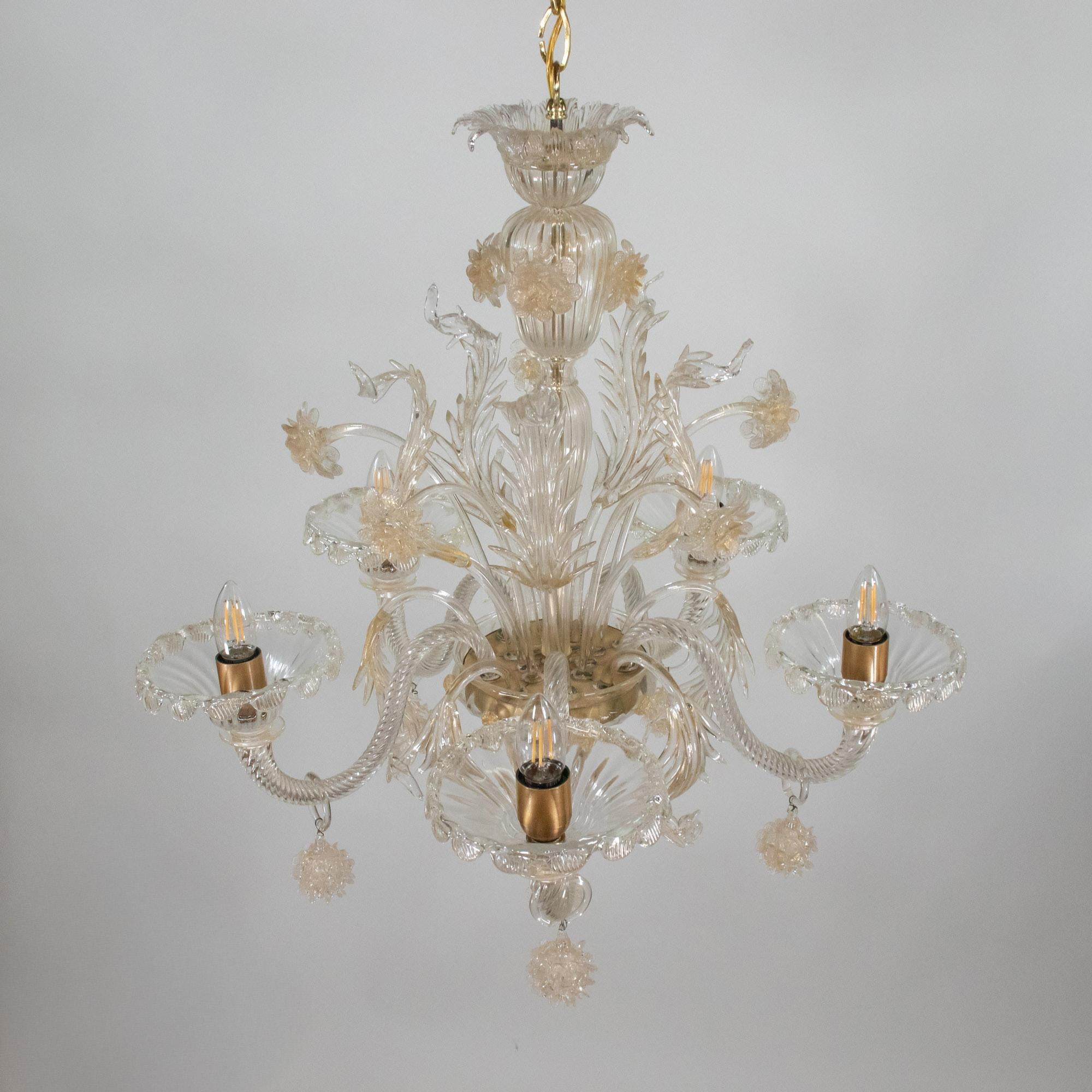 Dieser florale Murano-Kronleuchter im Barockstil verfügt über fünf wellenförmige Arme, die flache, mit Blütenblättern verzierte Bobeches halten, die aus unglaublich zartem, golddurchwirktem Cristallo-Glas handgefertigt sind. Jeder Arm ist außerdem
