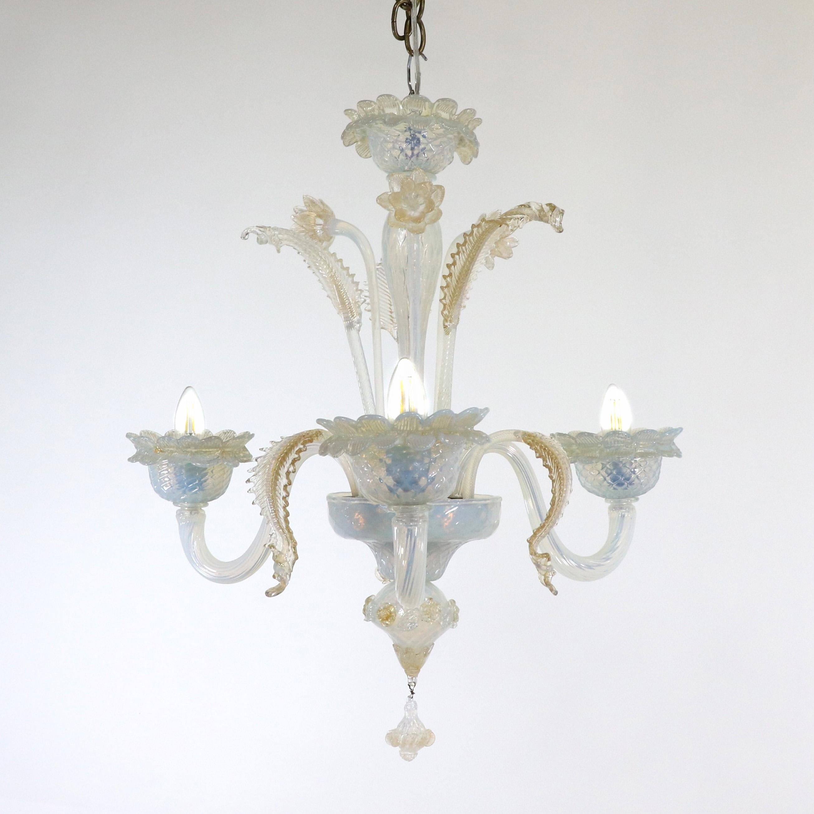This exquisitely handcrafted gold-infused opaline Murano chandelier has three flexing arms with petal trimmed cups. The milky opaline glass veers towards a light blue color with subtle changes in the light. Flowers and leaves embellish this glass