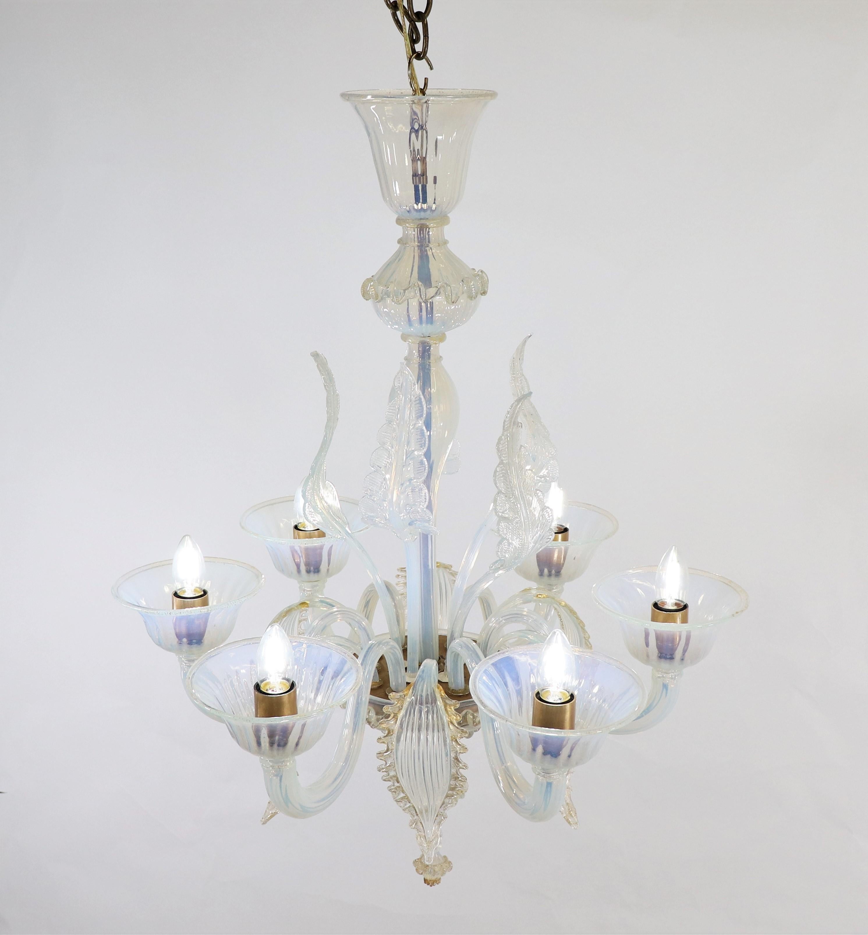 Questo lampadario opalino di Murano, squisitamente realizzato a mano, è caratterizzato da sei bracci ondulati che si estendono dalla ciotola centrale. Il vetro opalino lattiginoso tende a una tonalità azzurra con sottili variazioni di luce. Le