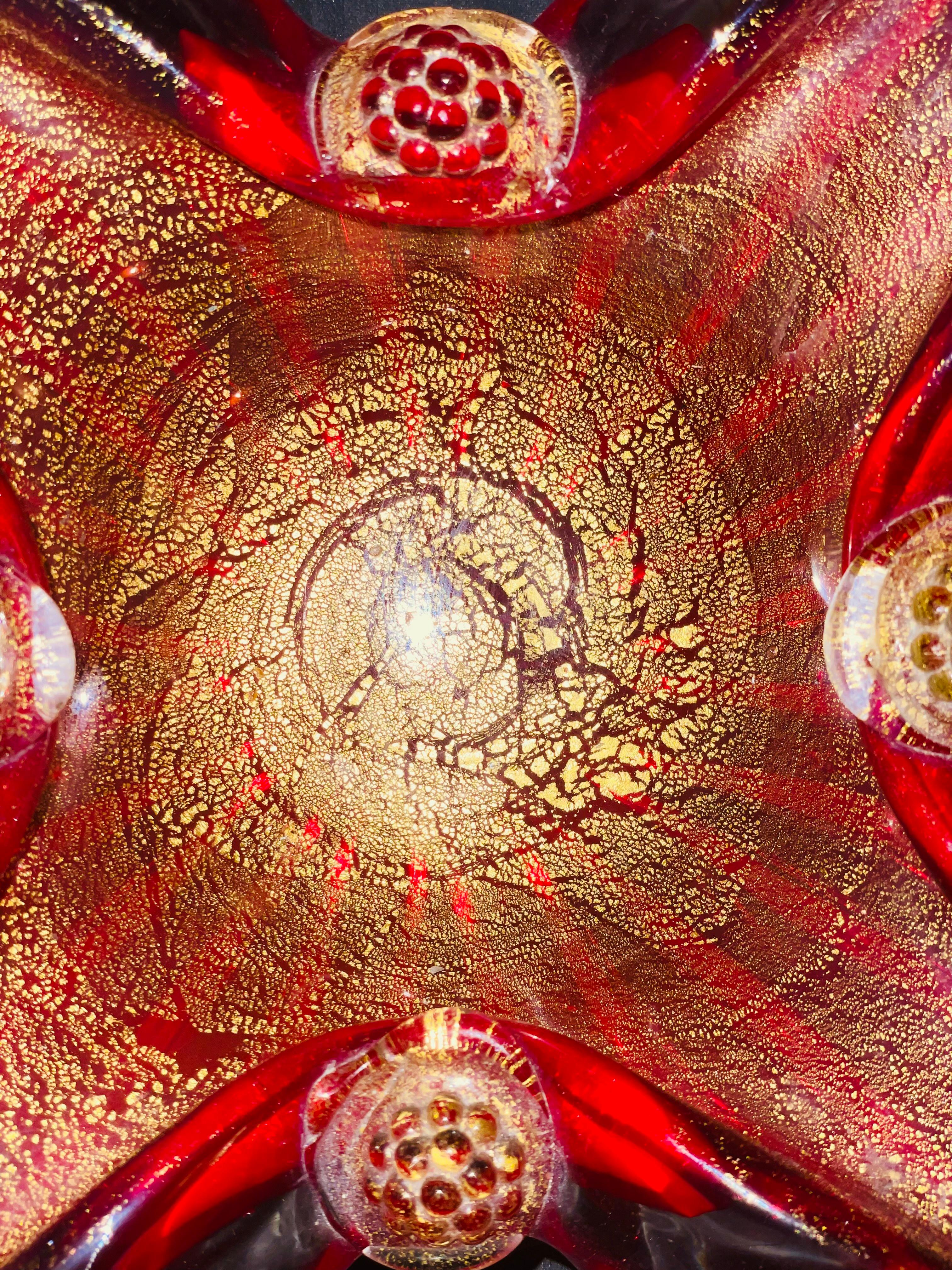 This Vintage Barovier & Toso Murano decorative bowl is a stunning example of Italian mid-century art glass.

Crafted in a rich ruby red with delicate gold leaf flecks, the bowl’s elegant sparkle is further enhanced by its dramatic spiked corners.