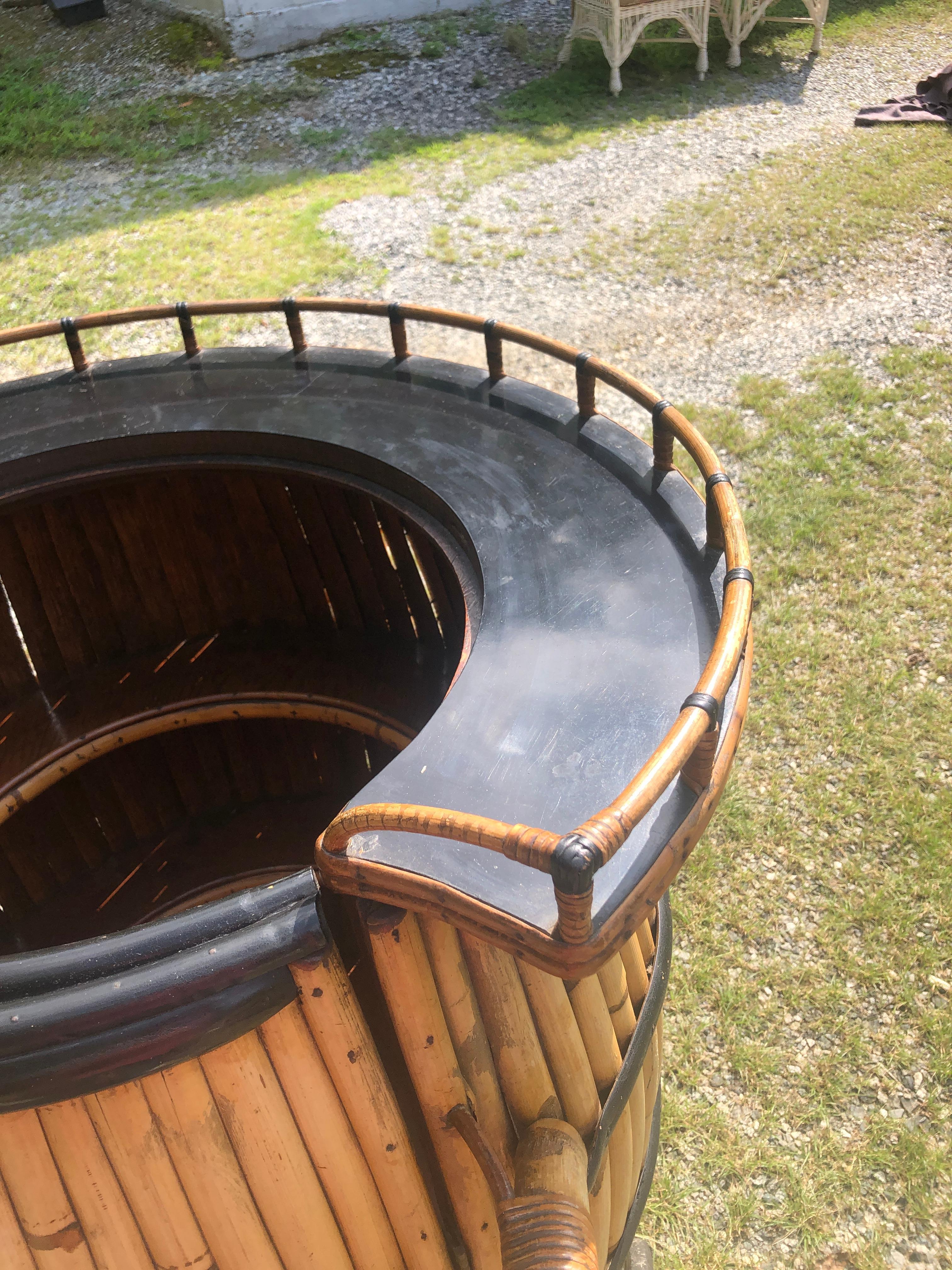 Un amusant et charmant bar vintage en rotin en forme de tonneau. Fabriqué à partir de bandes de rotin courbées et formées en forme de tonneau. Le bar s'ouvre pour révéler un espace de rangement conçu pour stocker les ustensiles de bar. La barre se