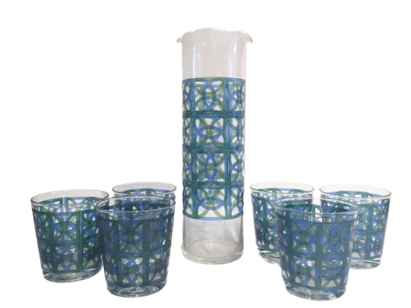 Mid-20th century cocktail set designed by Irene Pasinski for Washington Glass Co. West Virginia. Consisting of a double spouted cylindrical cocktail pitcher and six old fashioned glasses, all decorated with a geometric design in translucent blue and