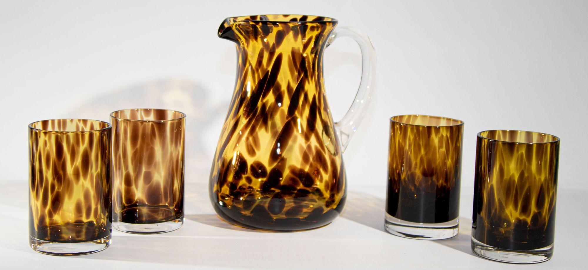 Vintage barware set of hand-blown glass pitcher with four glasses in a tortoise shell pattern.
Elegant barware hand blown tortoise shell glass pitcher amber with clear glass handle and glasses.
A distinctive tortoise shell motif brings rich color