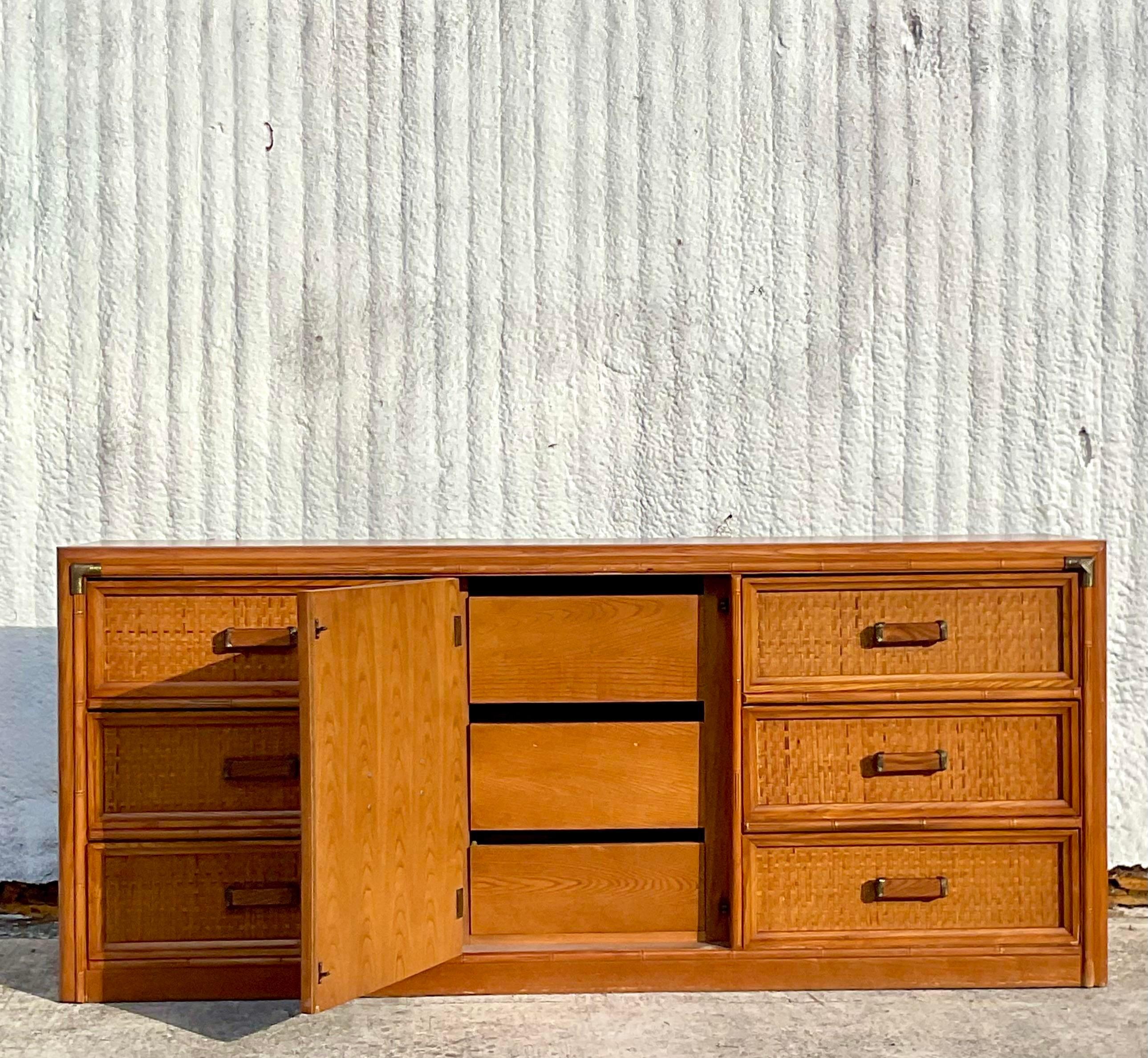 A fabulous vintage Coastal faux bamboo credenza. Made by the American Bassett Furniture group. Beautiful double door reveal an additional three drawers for storage. Acquired from a Palm Beach estate.