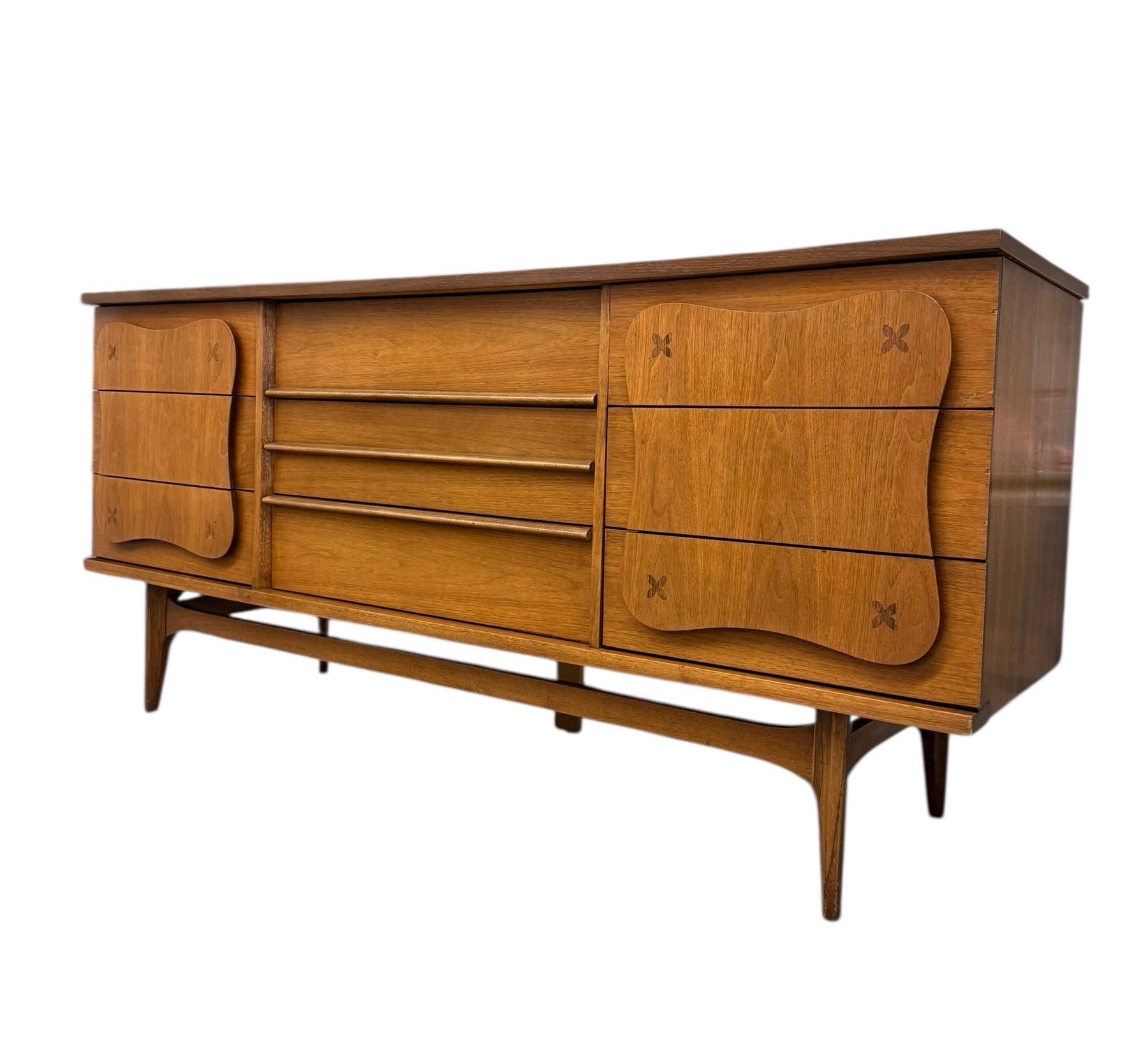 This rare Bassett Furniture dresser from the iconic “Monterey” line, designed by Leo Jiranek, was produced for only 10 months between 1962 and 1963. Crafted with a walnut veneer over solid wood, the set includes 5-drawer dresser and 9-drawer dresser