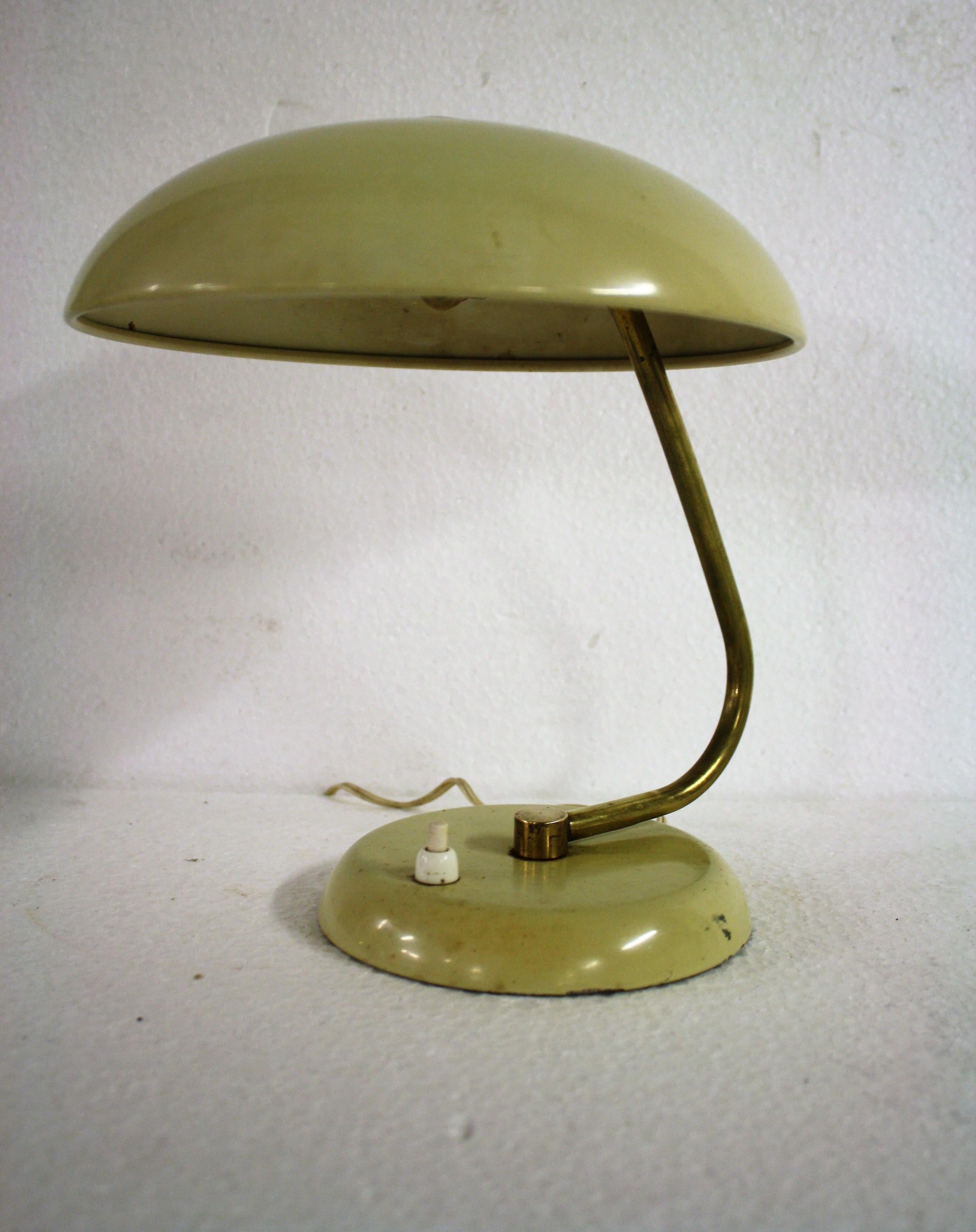 Late Bauhaus period beige table lamp with a brass arm.

The shade is adjustable, making it very useful as a desk lamp, a work light or even a bedside table lamp.

The lamp has some user traces and comes with its original light bulb holder.

It