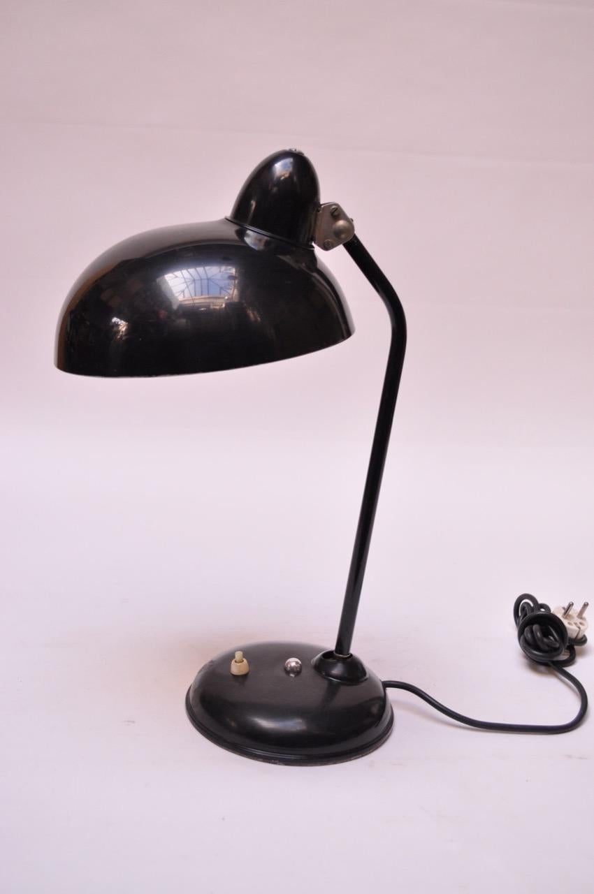 Desk/table lamp featuring a porcelain enamel shade and painted round metal base, circa 1930s. Features a fully adjustable shade. 
Shade shows only minor wear (light scratches); base shows dents and scratches, as pictured. 
Remains a practical,