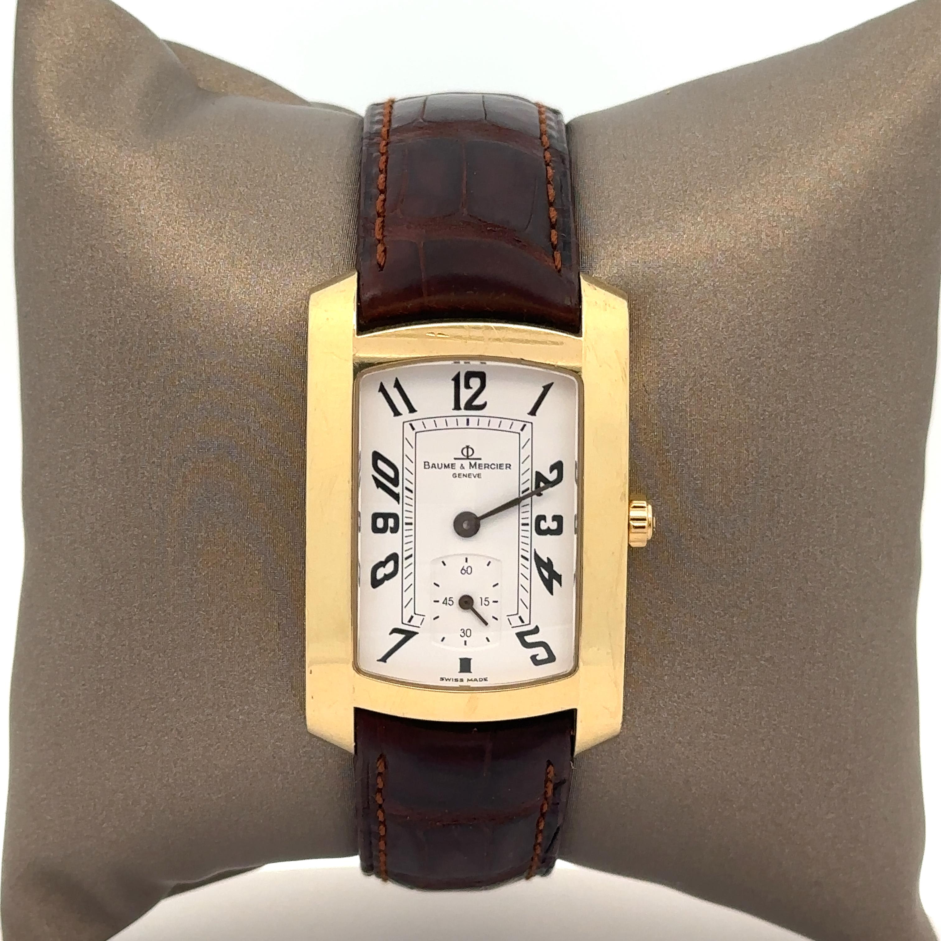 Watchmaker: Baume & Mercier
Movement: Quartz 
Case Material: Solid 18k Yellow Gold
Gross Weight:	51.6 Grams (including case, movement, and strap)
Case Width: 26mm (not including crown)
Case Height: 40.2mm (lug to lug)
Strap Type: Genuine Brown