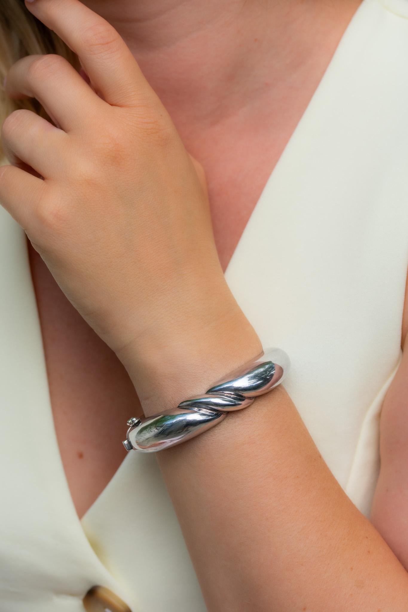 A vintage sculptural sterling silver bangle by Bayanihan, the celebrated jewellery house renowned for its bold, modernist designs. This hinged bracelet has a smooth, polished form accented by a sweeping wave motif across the front — simple and