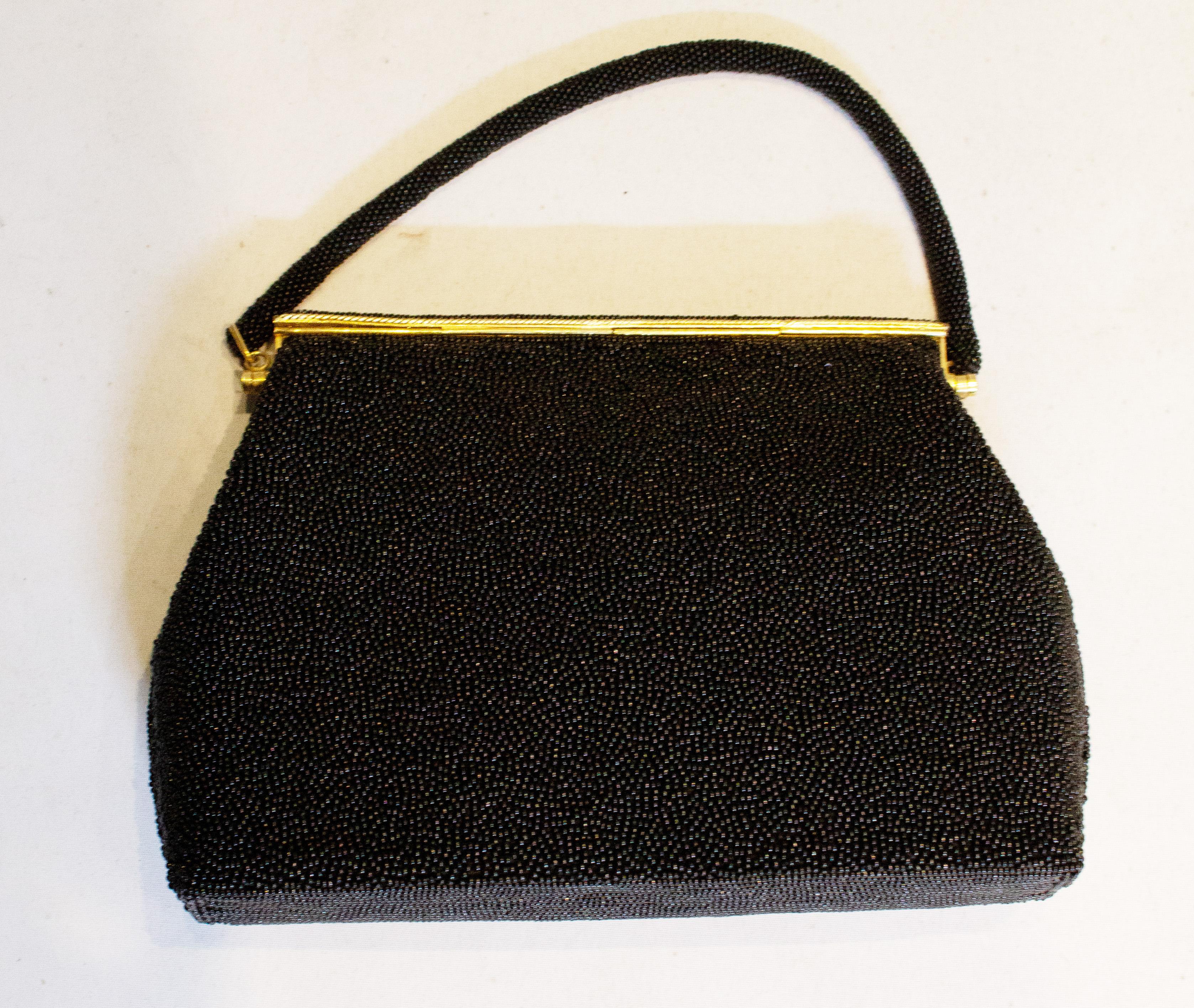 A pretty and unusual vintage handbag. The bag has a black beaded body apart from the front which has  a floral stitch design. It has a flapover clasp, and there is one internal pouch pocket. Measurement: width 10'', height 7''. depth 2'', strap 13''