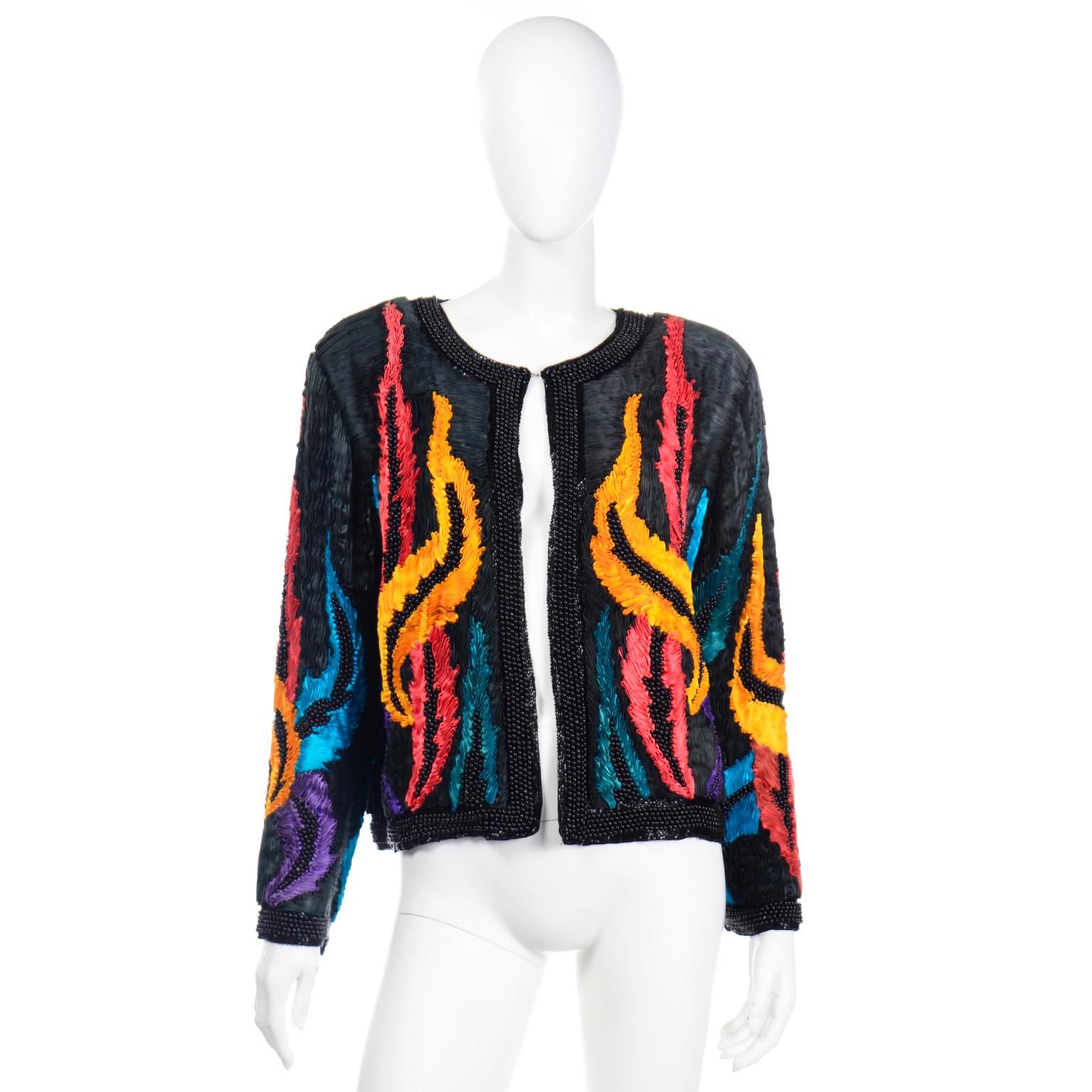 This is a very unique silk vintage beaded jacket with pleated soutache style detailing. This black jacket has ripples of fabric that give a 3d effect to the piece and it has strips of red, blue and marigold to give it even more interest.  The front