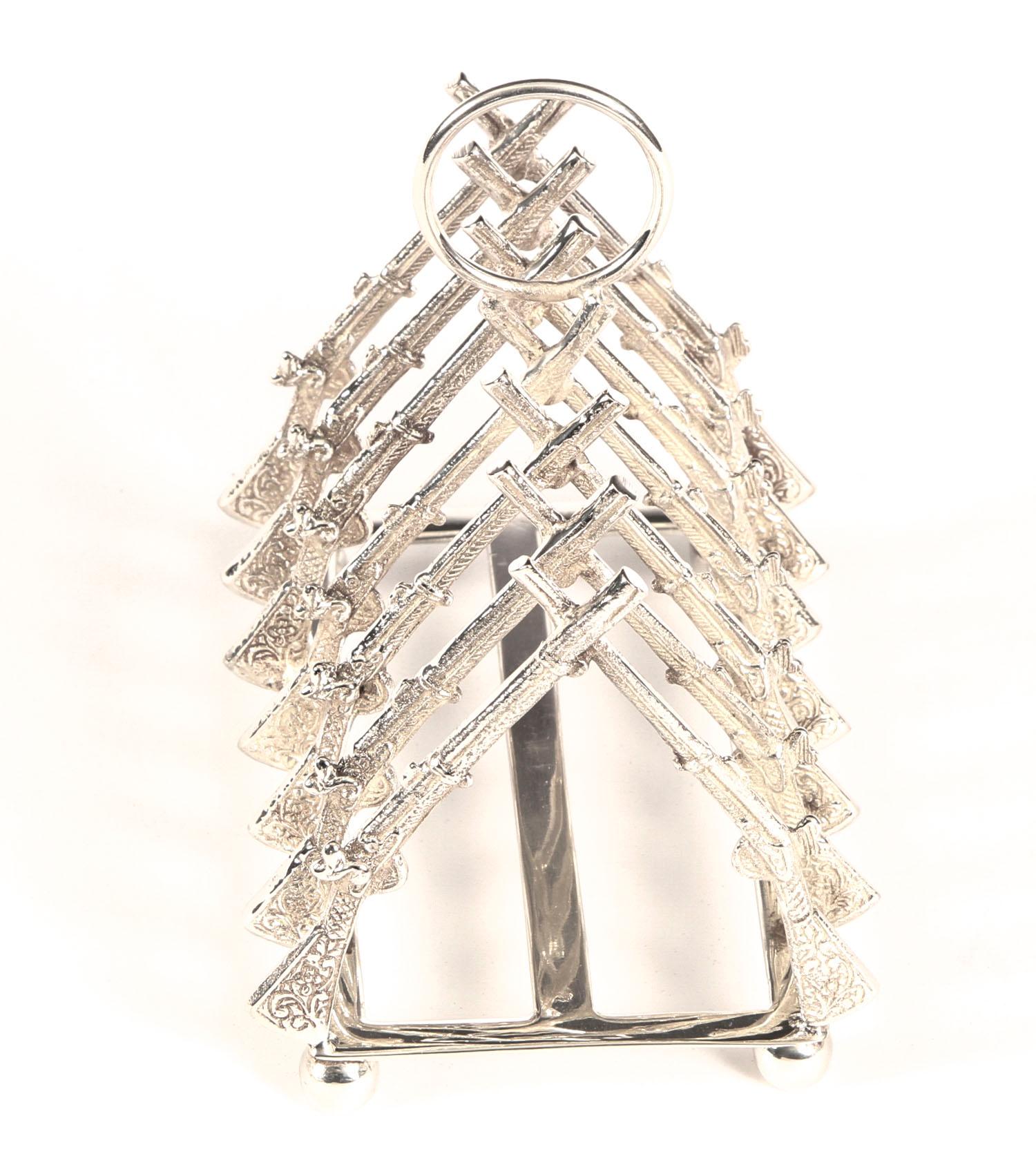 This is a delightful vintage silver plated crossed rifle toast rack dating from the late 20th Century.
 
The toast is held in place by crossed rifles.

Add touch of elegance to your breakfast table.
 
Ideal for the marksman in your