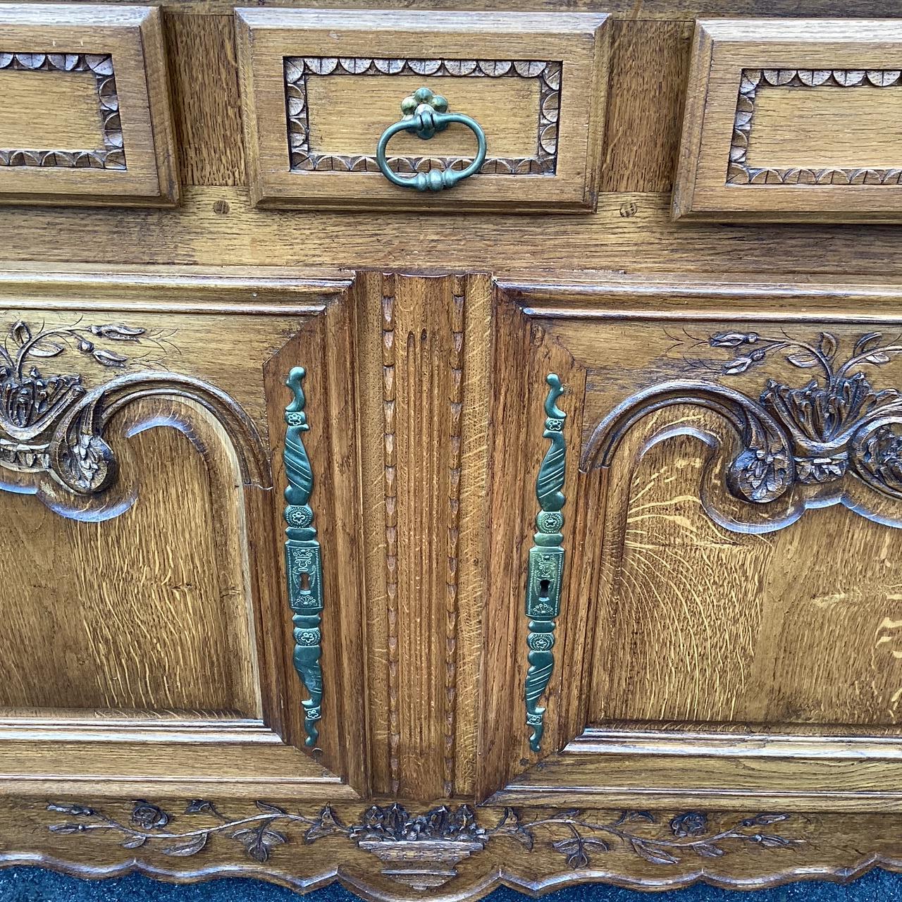 Elegantly carved impressive French oak buffe having bottom piece with 2 drawers, two doors, and lots of storage. The top tier features 2 larger doors with interior shelves. There are floral motifs on all the doors and baskets on the lower panel and