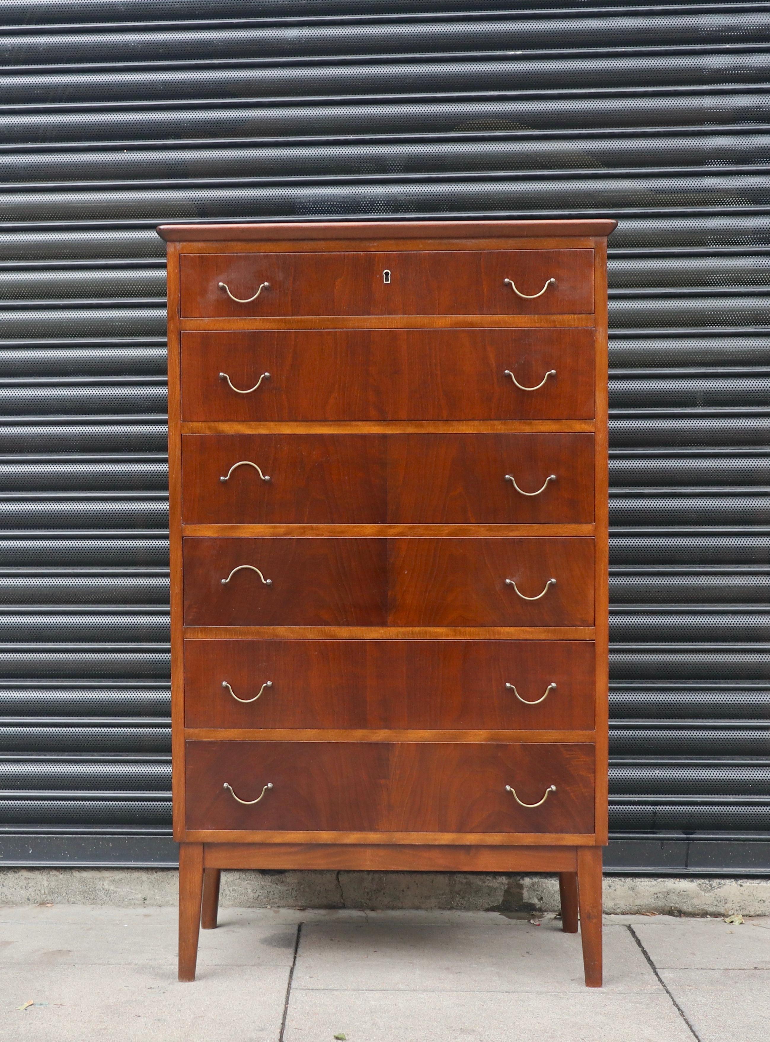 A vintage 1950s stained beech veneered seven drawer 'tall boy' chest of drawers on a solid beech base.  This piece is fitted with brass handles and is in good vintage condition, when you consider it's age. It is not only a good looking piece of