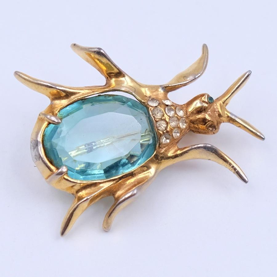 Cute and bright beetle brooch made of gold-tone metal. The core of the beetle is made of rhinestone imitating a topaz and decorated with small rhinestones. 
Materials: Base metal, glass
Height: 2.87 Inch
Hallmark: None
Period: 1940s