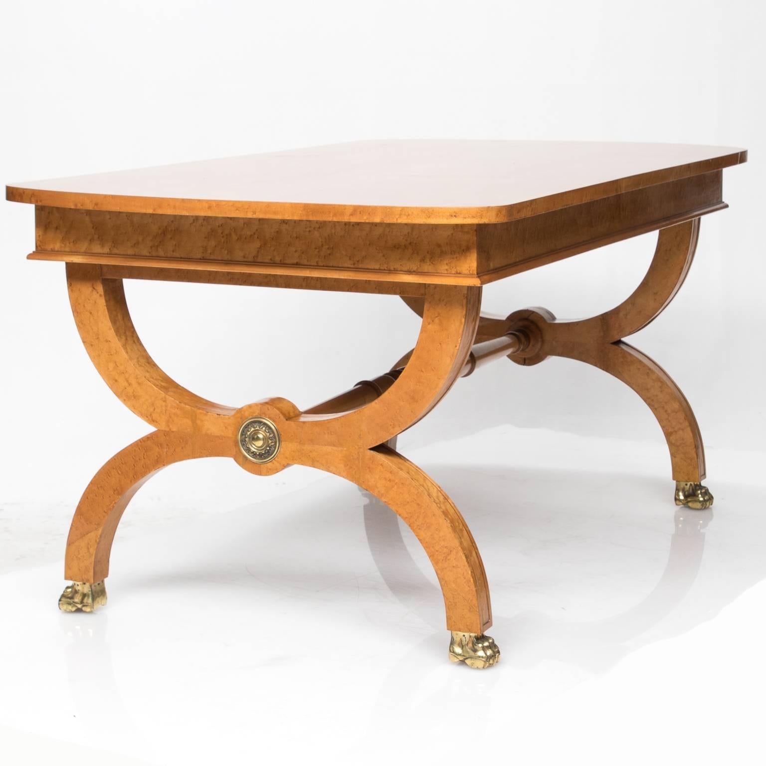 Purchased in France is this Fine bird's-eye maple Biedermeier style table with an elegant X-shaped supports connected with a turned stretcher. Brass mounts on supports and brass capped claw feet. Multifunctional table. Beautiful cuts of the