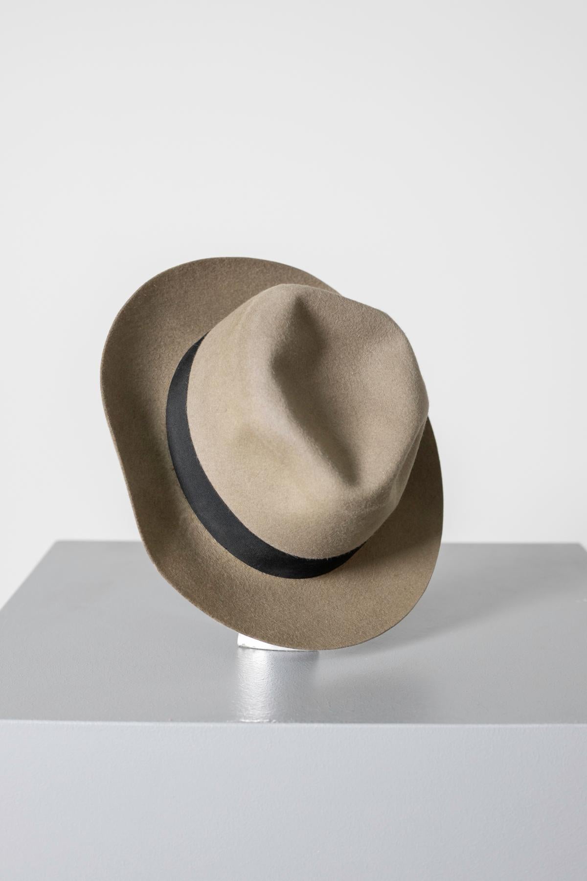 Joli chapeau en feutre beige du millésime des années 1990, belle fabrication italienne.
Le chapeau est entièrement en feutre
Le dôme porte 4 pinces souples.
À la base extérieure du dôme se trouve une bande noire avec un petit nœud sur la gauche.
A
