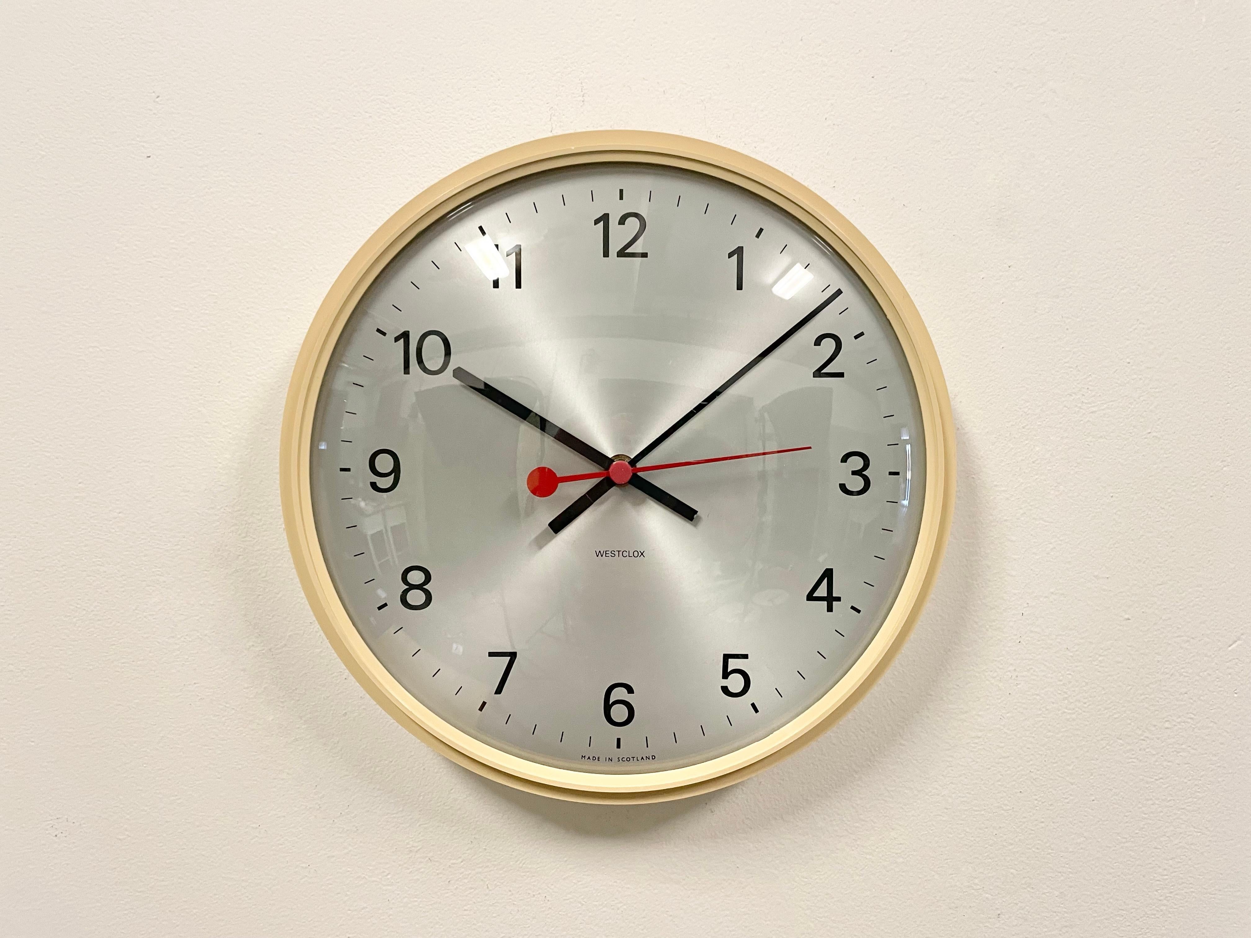 Vintage industrial wall clock produced by Westclox in Scotland during the 1970s. It features a beige bakelite frame, a silver dial, an aluminium hands and a curved clear glass cover. The piece has been converted into a battery-powered clockwork and