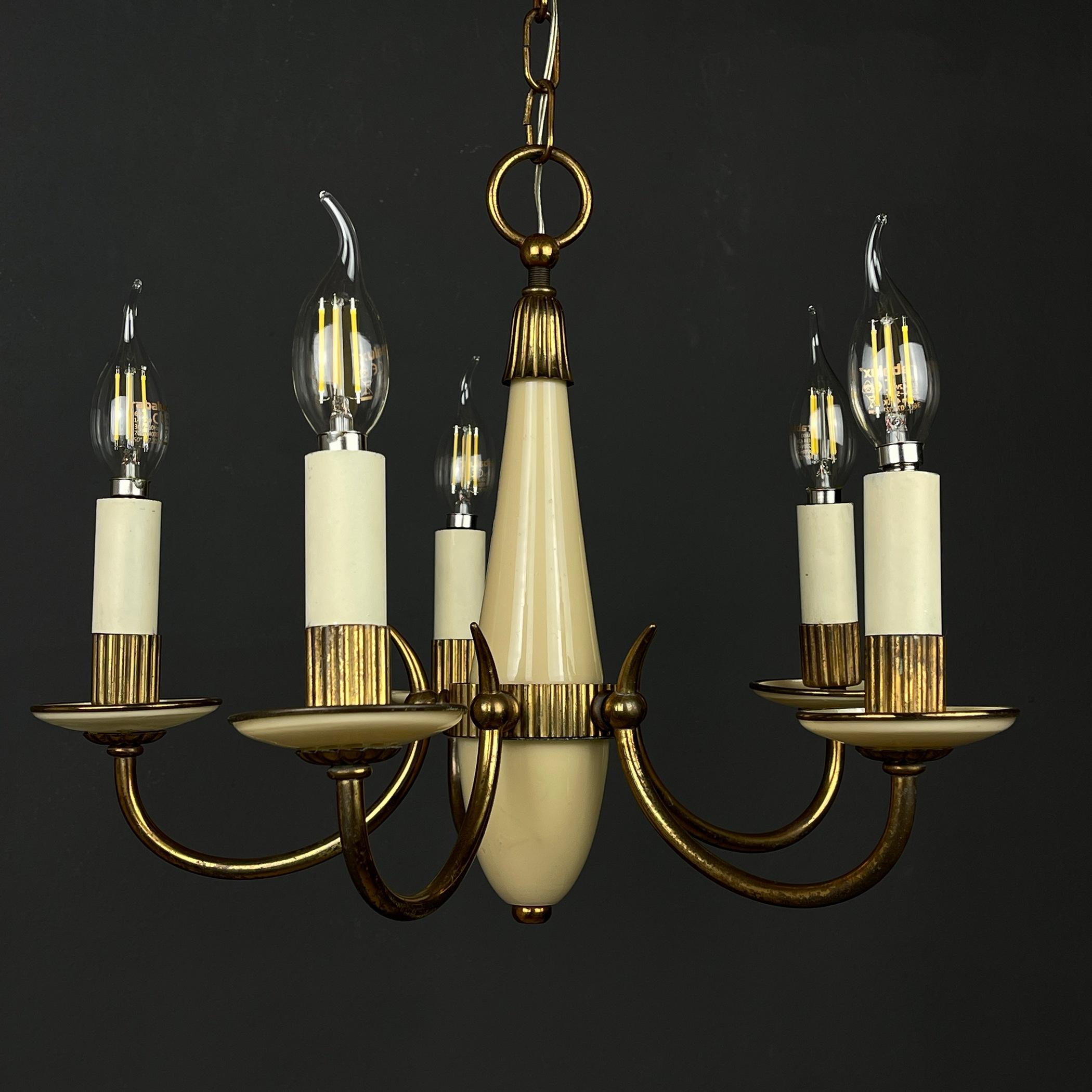 Illuminate your space with timeless charm through this exquisite vintage beige glass chandelier, lovingly crafted in Italy during the 1950s. This enchanting piece features 5 bronze arms adorned with delicate glass cups. In very good original